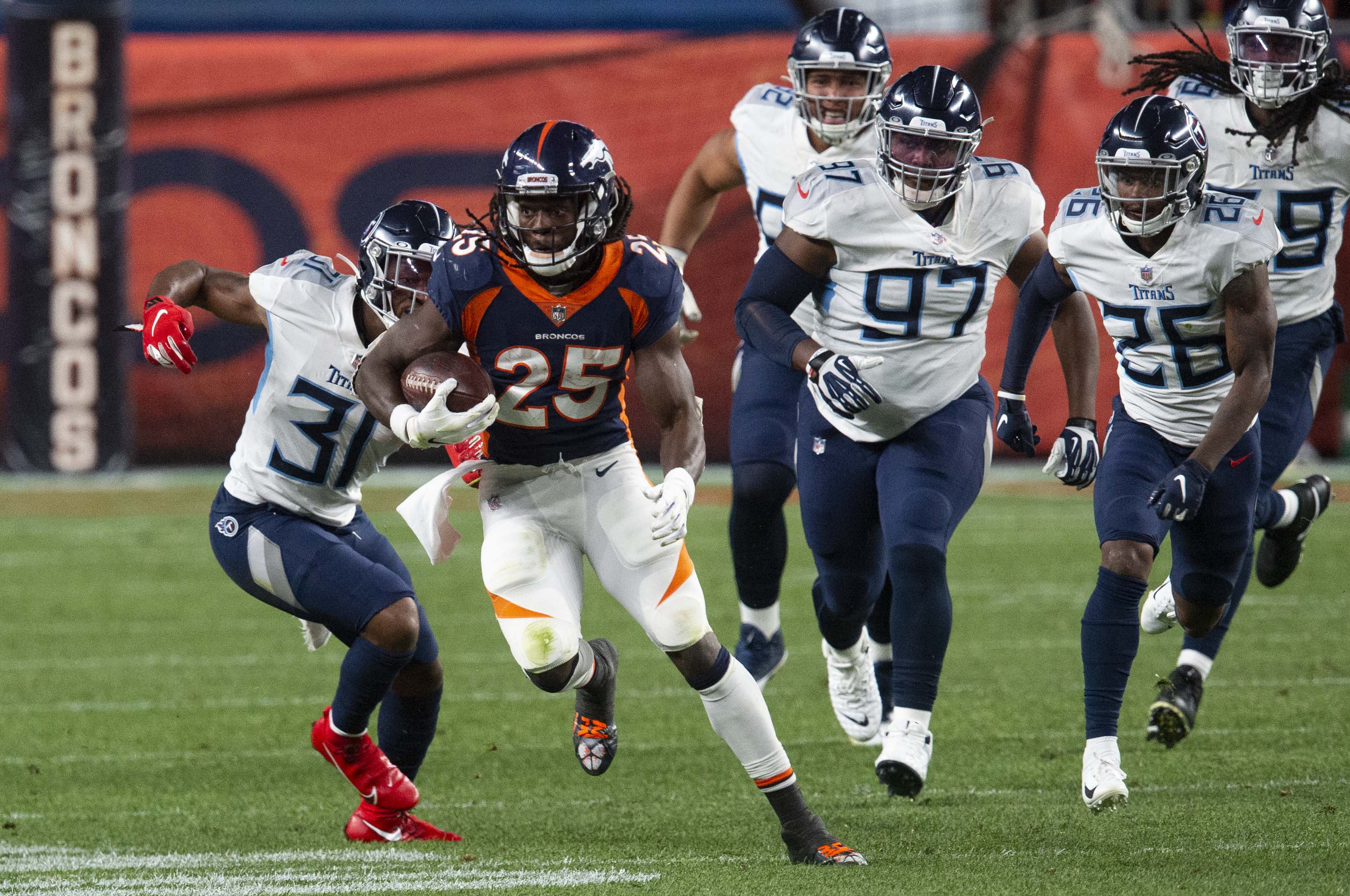 Denver Broncos running back Melvin Gordon (25) runs past Tennessee Titans free safety Kevin Byard (31), defensive tackle Isaiah Mack (97) and cornerback Kristian Fulton (26) for a first down during the third quarter Monday, Sept. 14, 2020, at Empower Field at Mile High in Denver.The Titans won 16-14. (The Gazette, Christian Murdock) (Christian Murdock/The Gazette)
