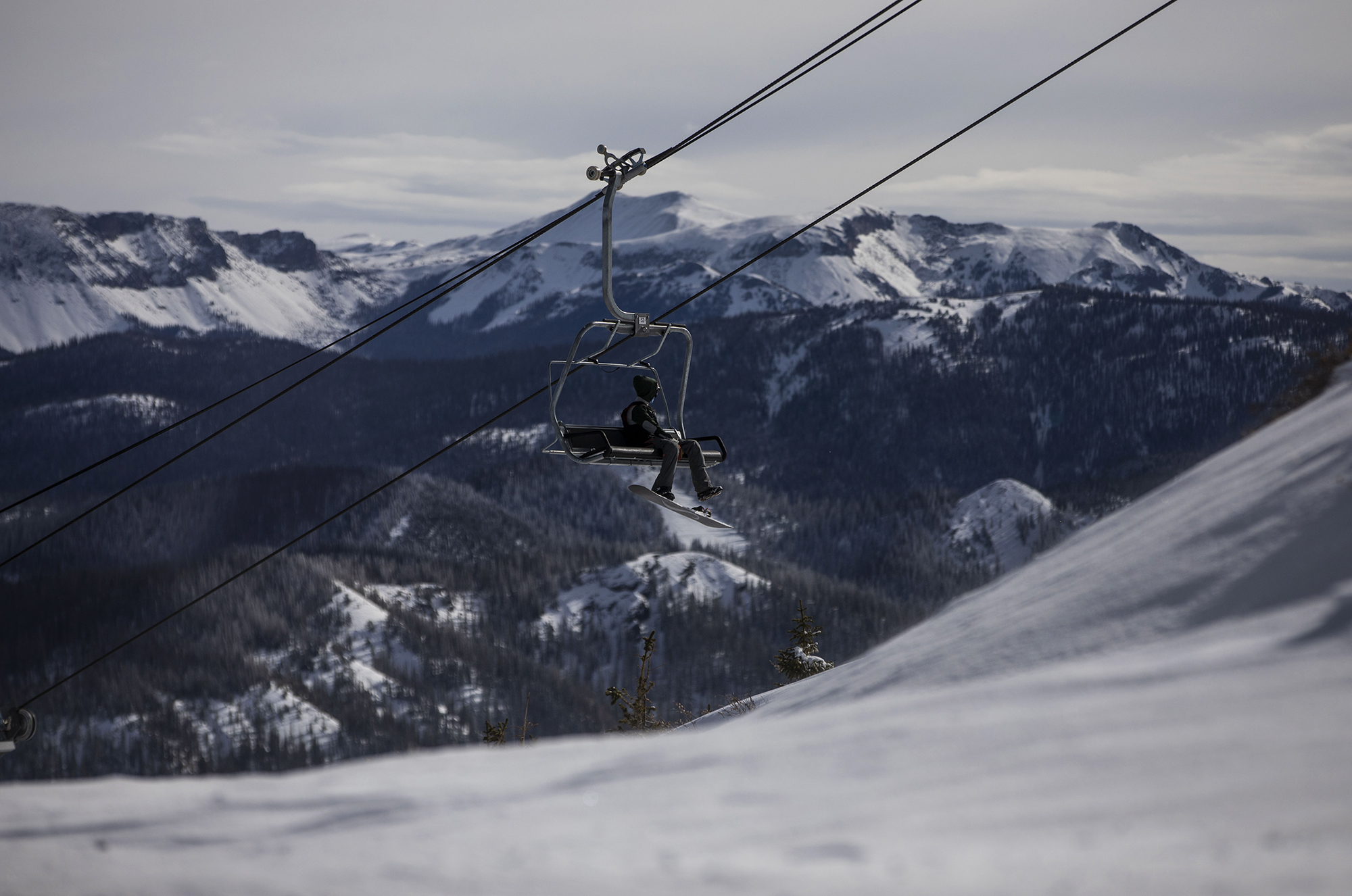 A snowboarder rides the Treasure ski lift at Wolf Creek Ski Area in Colorado on Wednesday, Oct. 28, 2020. Wolf Creek is the first ski area in Colorado to open for the 2020-21 season, with a snow total of 24 inches. Treasure, Bonanza and Nova lifts are in full operation. Due to COVID-19, all indoor facilities are closed, excluding bathrooms, social distancing and wearing of masks are required. (Chancey Bush/ The Gazette) (Chancey Bush The Gazette)