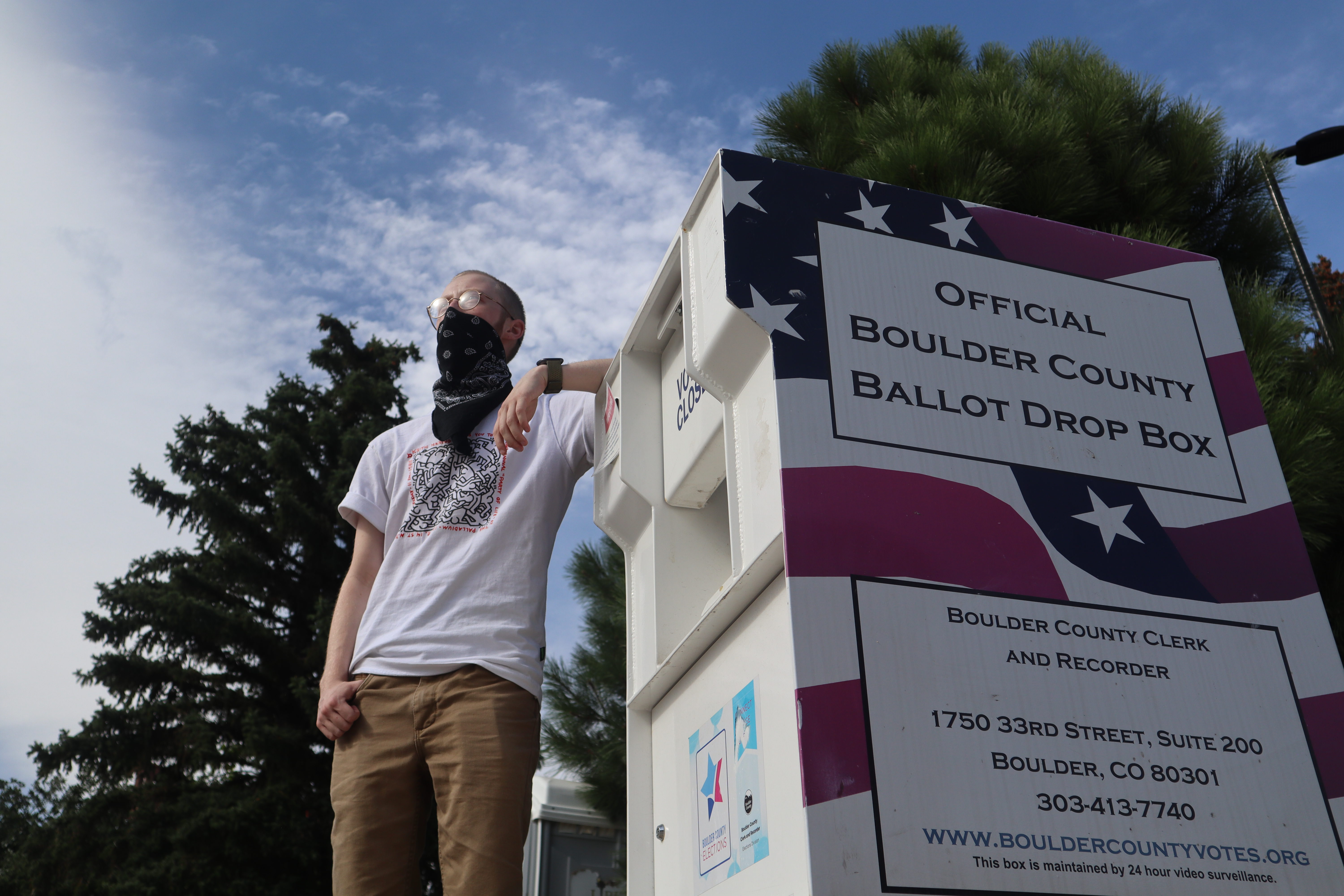University of Colorado Boulder student Shay Mannik, 20, stands next to a Boulder County ballot drop box in September. (Robert Tann, special to the gazette)