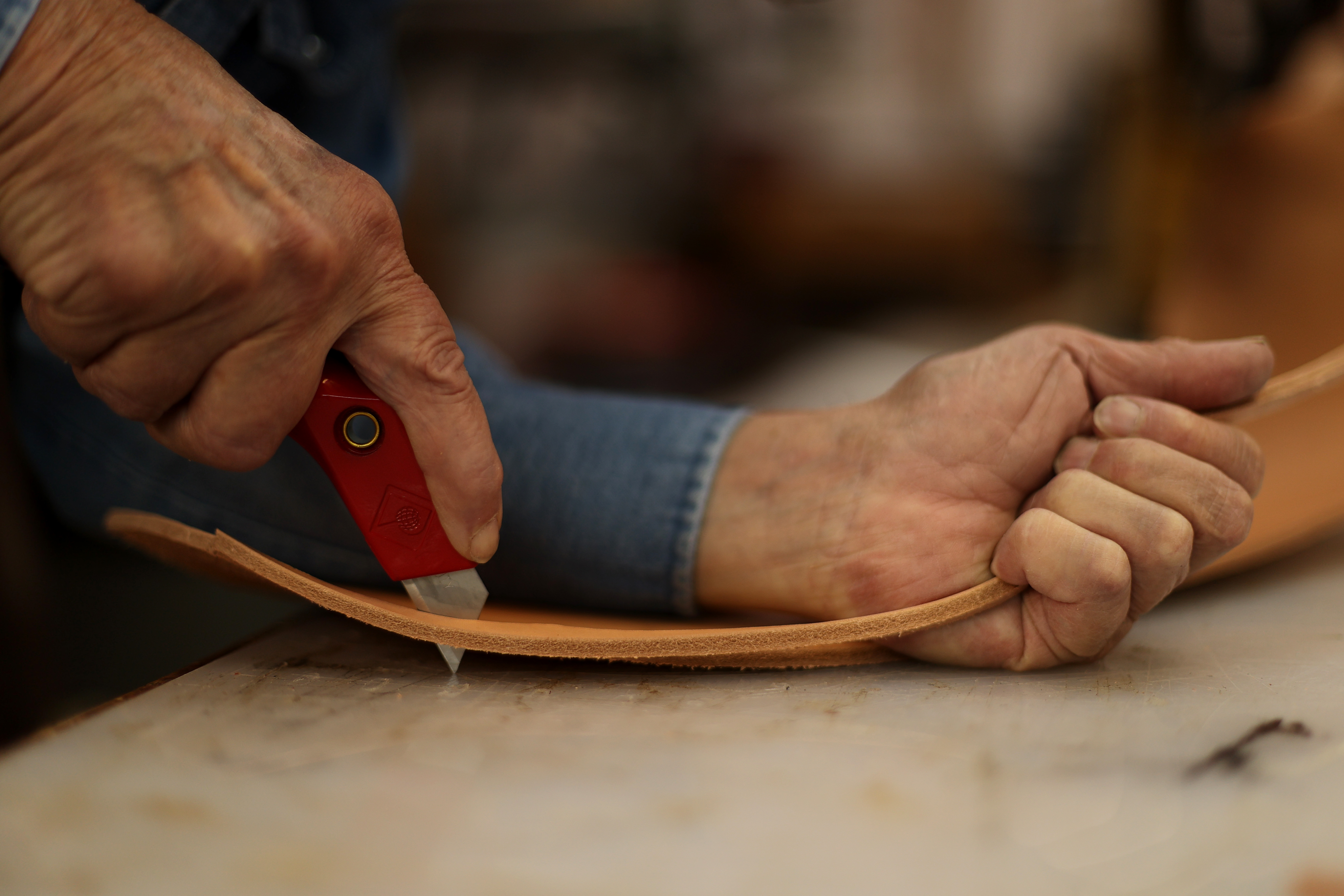 Bob Brenner cuts out a breast collar pattern while working in his saddle shop in Black Forest last month. (Forrest Czarnecki)