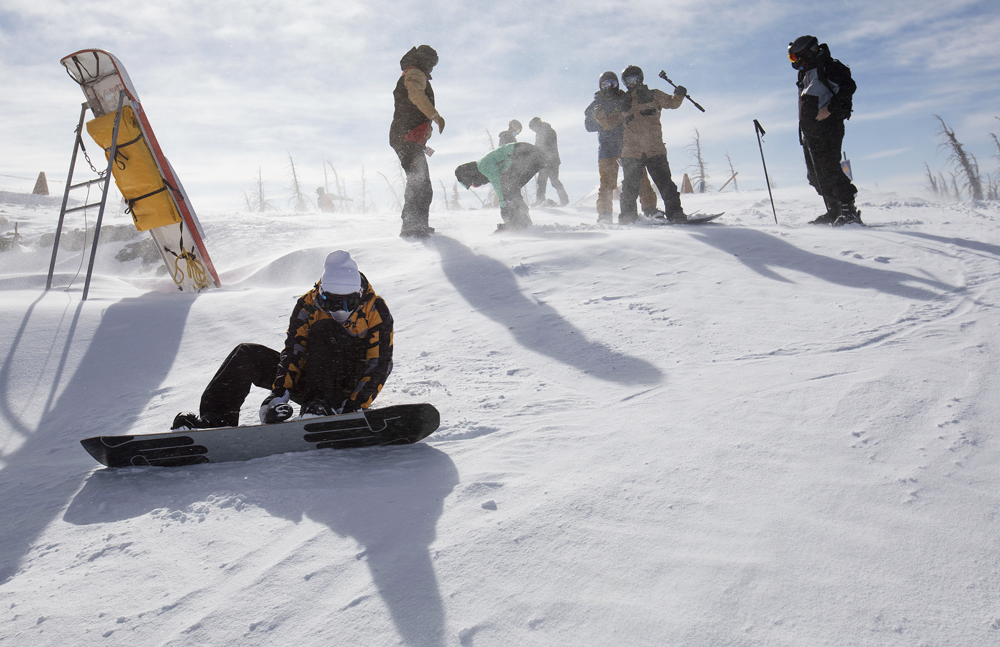 Snowboarders strap in as the wind blows snow at the top of the Treasure ski lift at Wolf Creek Ski Area in Colorado on Wednesday, Oct. 28, 2020. Wolf Creek is the first ski area in Colorado to open for the 2020-21 season, with a snow total of 24 inches. Treasure, Bonanza and Nova lifts are in full operation. Due to COVID-19, all indoor facilities are closed, excluding bathrooms, social distancing and wearing of masks are required. (Chancey Bush/ The Gazette) (Chancey Bush The Gazette)
