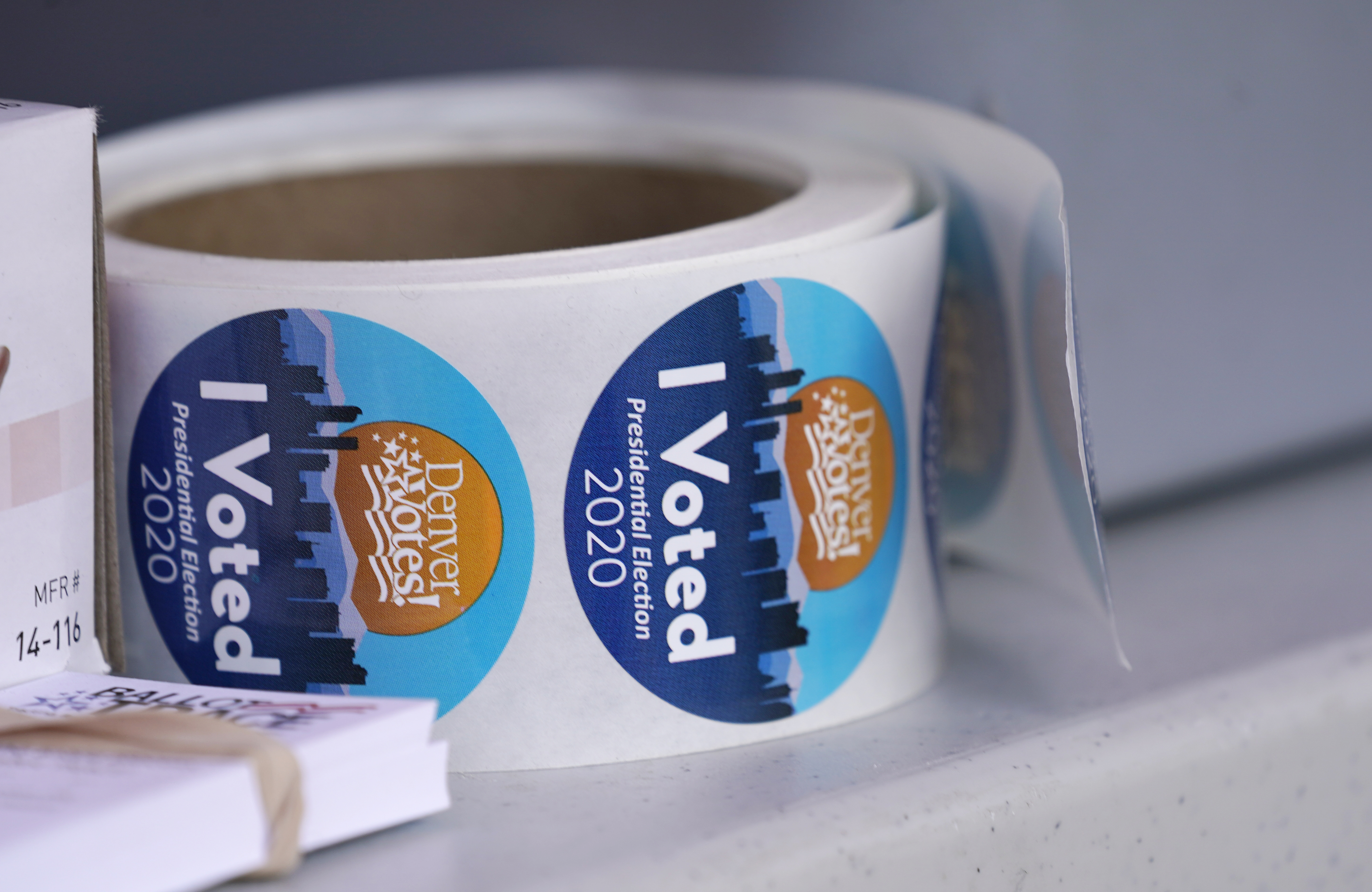 A roll of stickers to hand out to voters turning in their ballots sits on a table at a drive-up drop off site for voters outside the Denver Election Commission office Thursday, Oct. 15, 2020, in downtownDenver. (The Associated Press)