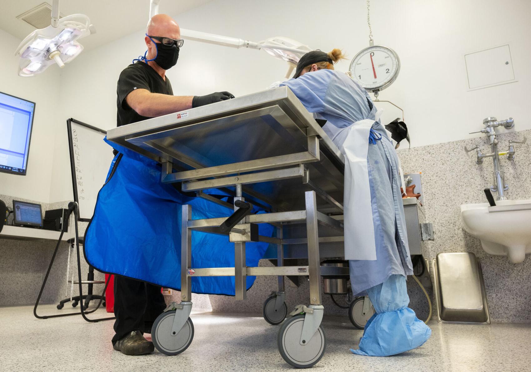 El Paso County coroner Dr. Leon Kelly, left, and autopsy technician Hannah Brunner examine a corpse of a possible COVID-19 casualty Friday morning, Dec. 4, 2020, at the El Paso County Coroner’s Office in Colorado Springs. (The Gazette, Christian Murdock)