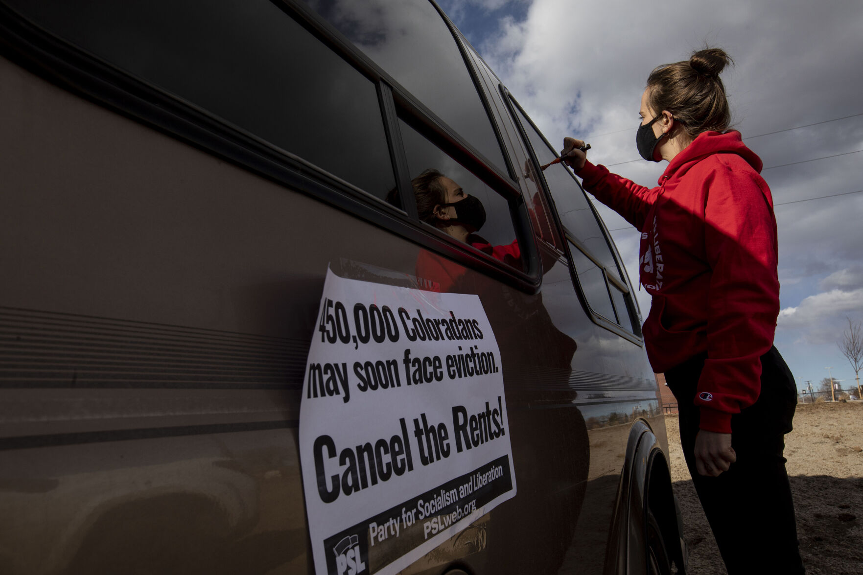 Elle Taylor writes on windows in preparation for the Denver chapter of the Party for Socialism and Liberation and 9to5 Colorado hold a ‘Cancel the Rent’ car protest in Denver, Colo., on Saturday, Jan. 30, 2021. The protest was a national day of action with 30 planned for this weekend by PSL chapters in cities around the U.S to ask for government intervention to head off a worsening housing crisis. The concern over eviction moratoriums expiring in April will mean a renewed wave of evictions for residents in Colorado. 