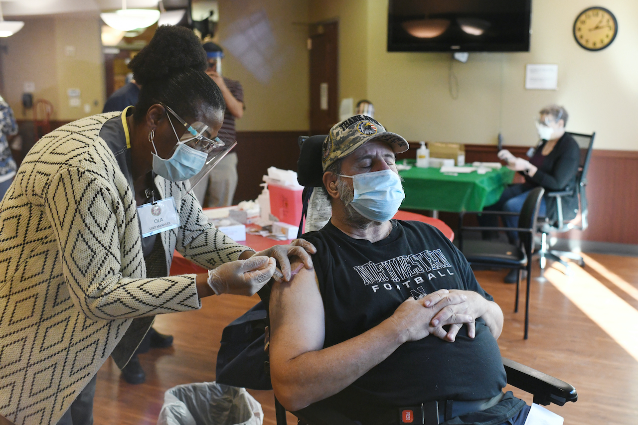 AURORA, CO - DECEMBER 22 : Registered nurse Ola Arije, left, administers a COVID-19 vaccine to Army Veteran Phil Ross, 73, at Veterans Community Living Center at Fitzsimons in Aurora, Colorado on Tuesday, December 22, 2020. Ross is the first senior received the vaccine in Colorado. Residents and staff of the Fitzsimons veterans facility is among the first seniors in the state to receive the COVID-19 vaccine. (Photo by Hyoung Chang/The Denver Post) (Hyoung Chang)