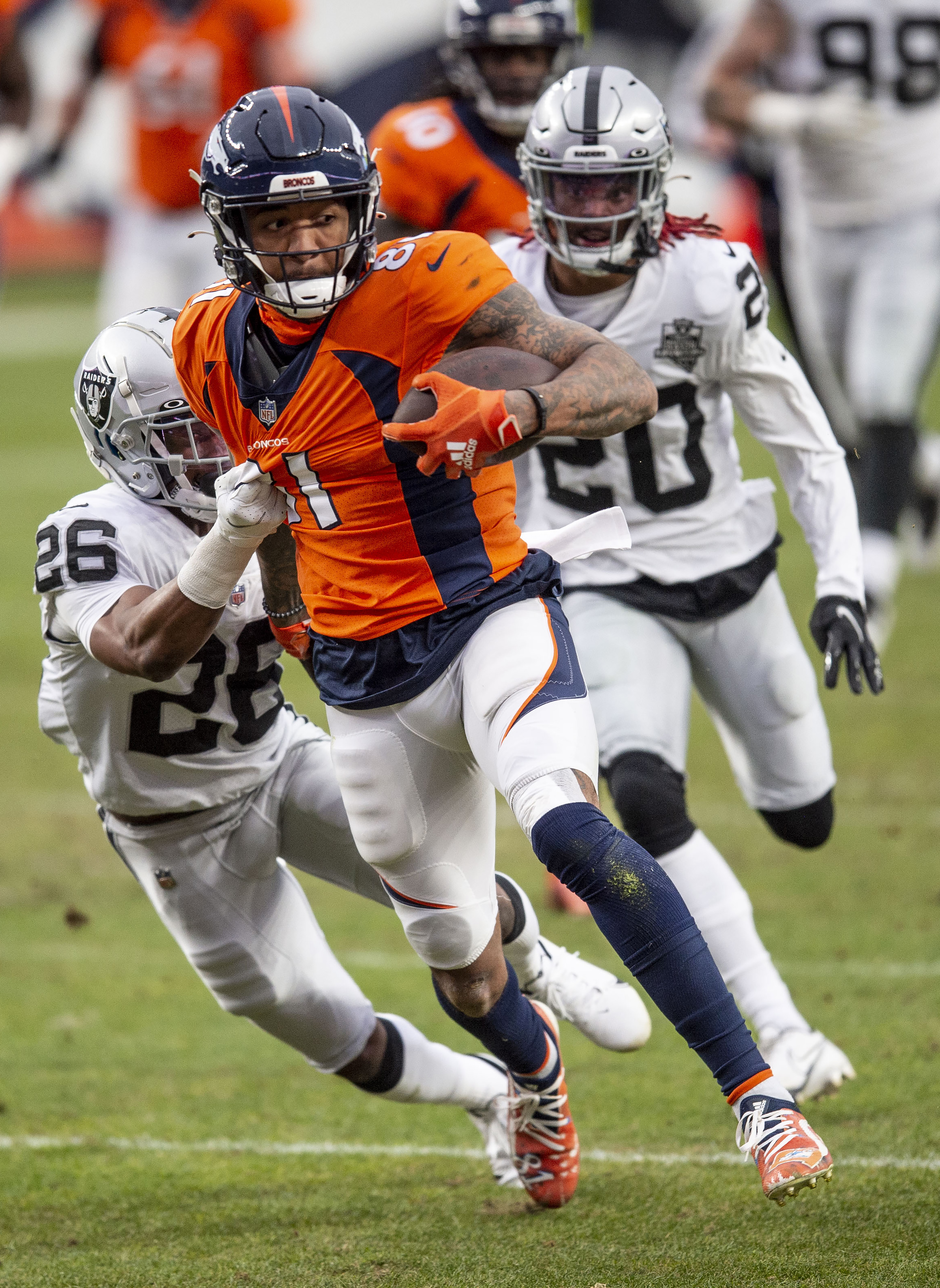 Denver Broncos wide receiver Tim Patrick (81) carries the ball as Las Vegas Raiders cornerback Nevin Lawson (26) latches on for the tackle as the Denver Broncos take on the Las Vegas Raiders at Empower Field at Mile High in Denver, Colo., on Sunday, Jan. 3, 2021. (Chancey Bush/ The Gazette) (Chancey Bush/ The Gazette)