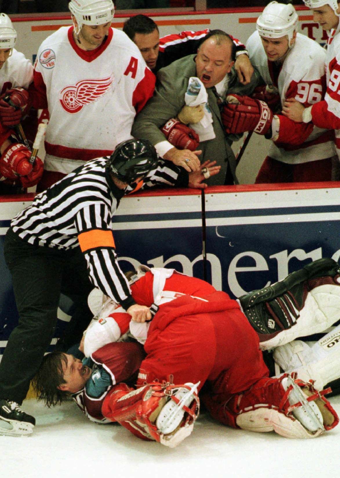 Referee Terry Gregson warns Detroit Red Wings coach Scotty Bowman to stay back as Red Wings goalie Chris Osgood and Colorado Avalanche goalie Patrick Roy fight in front of the Wings bench in the third period in Detroit on April 1, 1998. (Associated Press file photo)
