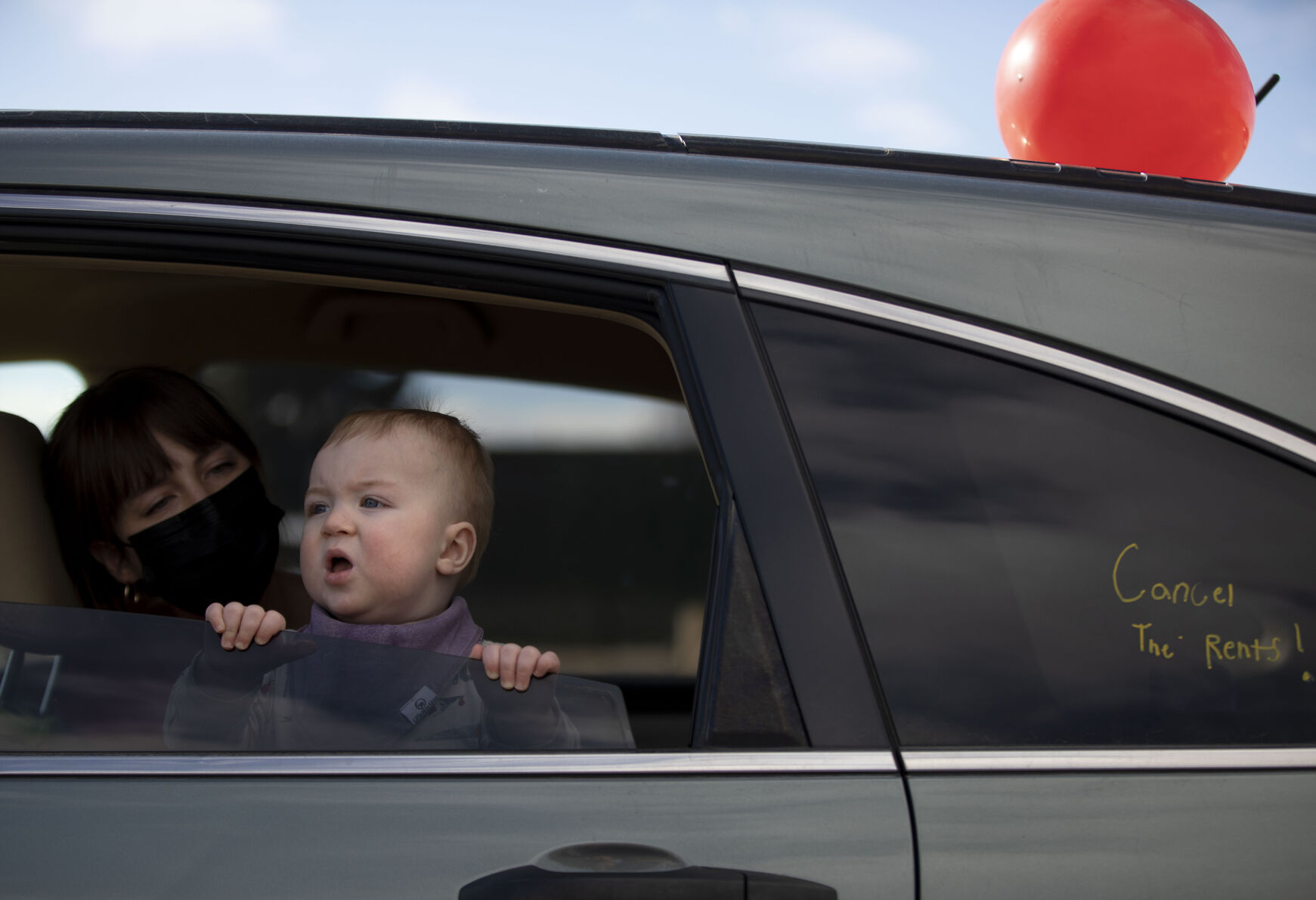 Cosmo Ruch peeks out of a car window with his mother Moira Casados Cassidy in preparation for the Denver chapter of the Party for Socialism and Liberation and 9to5 Colorado hold a ‘Cancel the Rent’ car protest in Denver, Colo., on Saturday, Jan. 30, 2021. The protest was a national day of action with 30 planned for this weekend by PSL chapters in cities around the U.S to ask for government intervention to head off a worsening housing crisis. The concern over eviction moratoriums expiring in April will mean a renewed wave of evictions for residents in Colorado. 