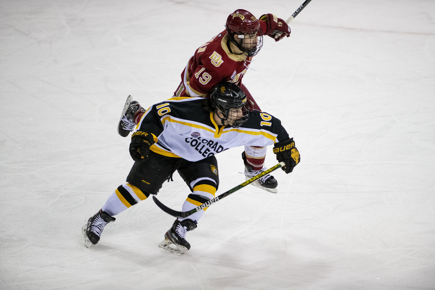 Colorado College sophomore forward Patrick Cozzi (10) and Denver junior forward Cole Guttman (19) race for the puck during the Battle for the Gold Pan at The Broadmoor World Arena in Colorado Springs on Thursday, Feb. 25, 2021. (Chancey Bush/ The Gazette) (Chancey Bush/ The Gazette)