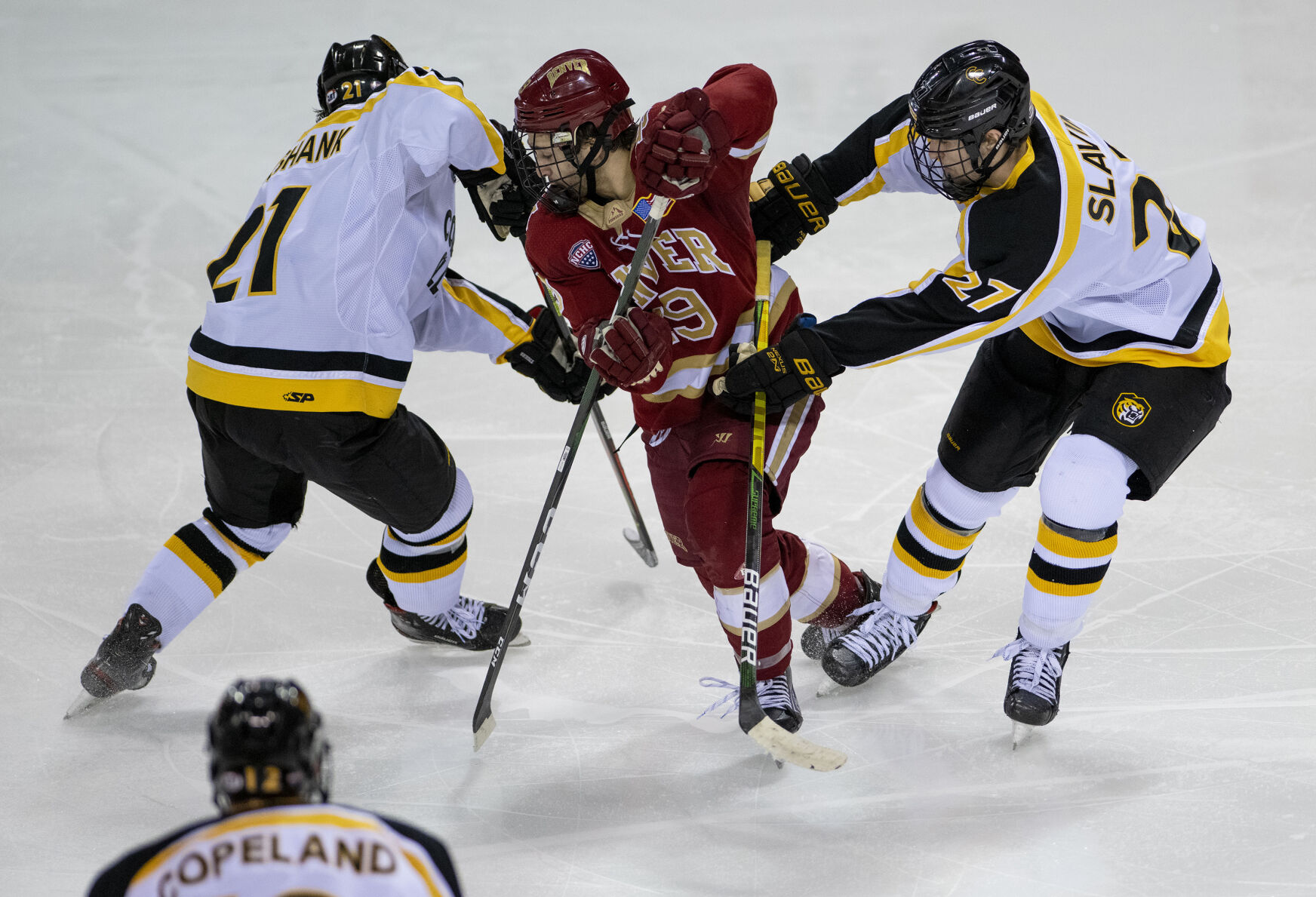 Denver junior forward Cole Guttman (19) gets blocked by Colorado College junior forward Grant Cruikshank (21) and sophomore forward Josiah Slavin (27) during college hockey game as the CC Tigers and DU Battle for the Gold Pan at The Broadmoor World Arena in Colorado Springs on Thursday, Feb. 25, 2021. Denver won the game against the CC Tigers by a score of 5 to 1. (Chancey Bush/ The Gazette) (Chancey Bush/ The Gazette)
