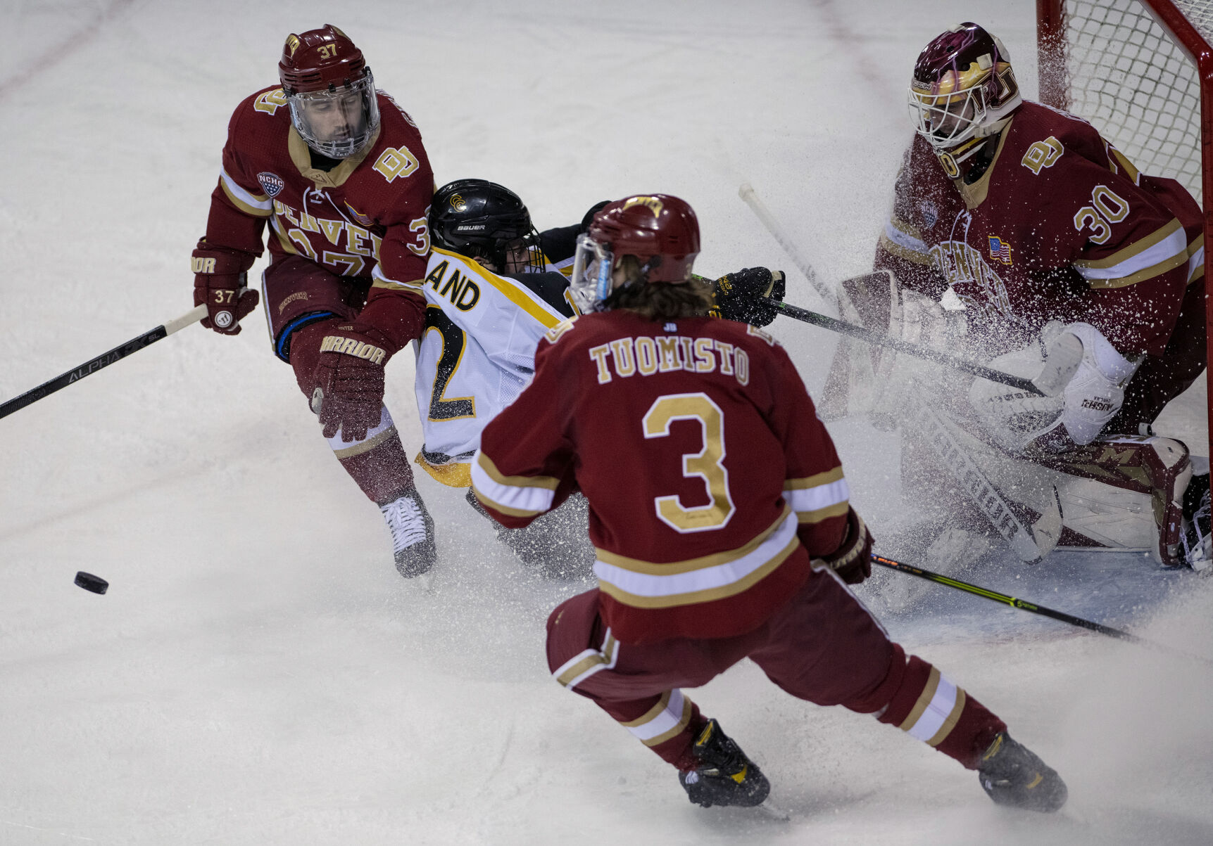 Colorado College junior forward Ben Copeland (12) slides into Denver sophomore goalie Magnus Chrona (30) during college hockey game as the CC Tigers and DU Battle for the Gold Pan at The Broadmoor World Arena in Colorado Springs on Thursday, Feb. 25, 2021. Denver won the game against the CC Tigers by a score of 5 to 1. (Chancey Bush/ The Gazette) (Chancey Bush/ The Gazette)