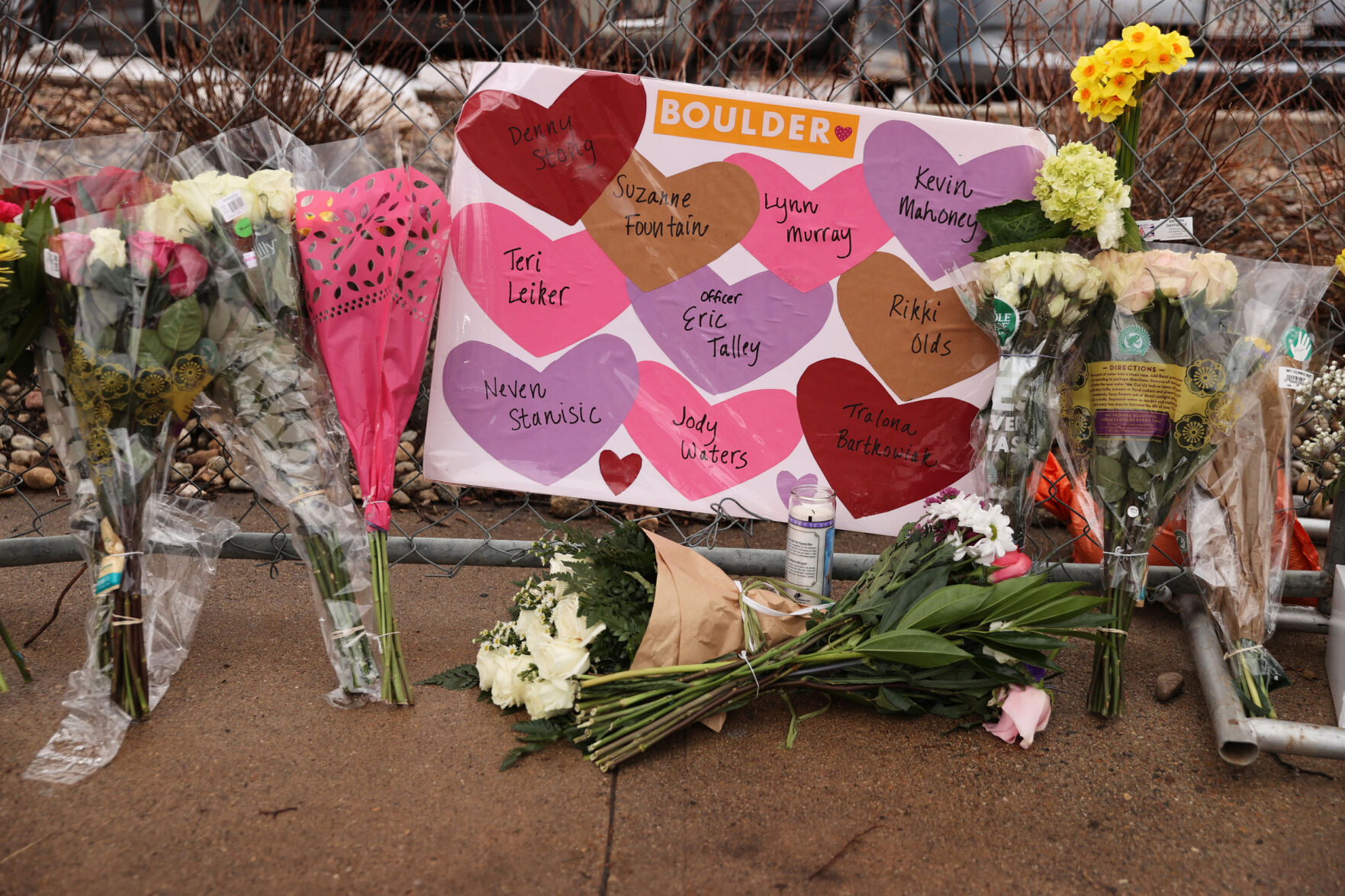 A sign with the names of the victims rests among bouquets at the King Soopers on Table Mesa Drive in Boulder on Tuesday. (Forrest Czarnecki)