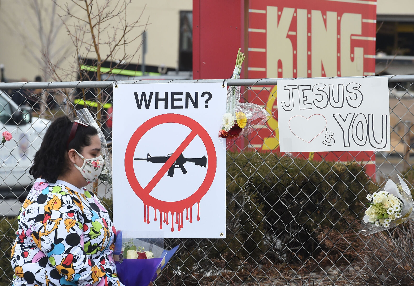 Tanice Cisneros walks by an anti-gun sign on the way to leave flowers for her friend, Rikki Olds, on Tuesday. Olds was a King Soopers employee who was killed at the Boulder King Soopers on Monday. (photos by JERILEE BENNETt, the gazette)