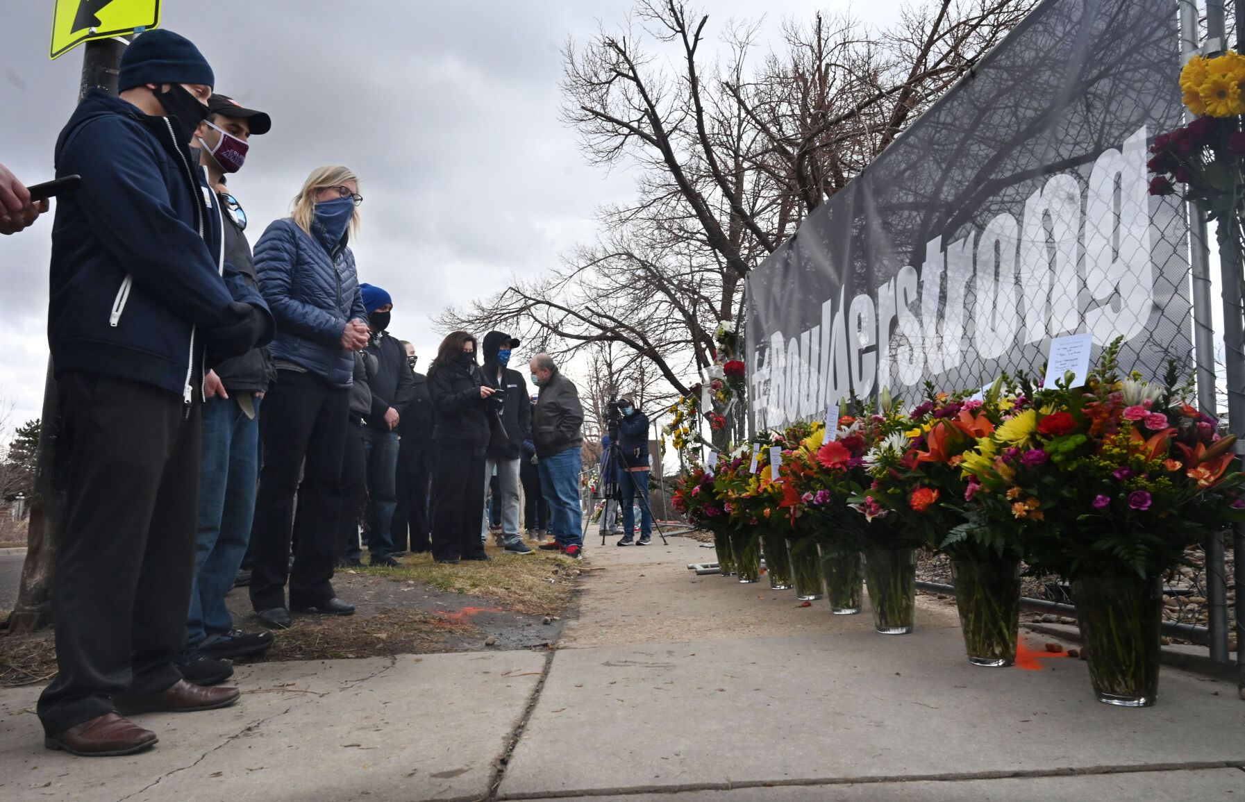 ABOVE: Boulder Police Chief Maris Herold waits to speak outside the police department on Tuesday. AT LEFT: A solemn group of King Soopers employees, some from the Boulder store and some from the same district, brought large sprays of flowers for each of the victims of a mass shooting at a Boulder King Soopers store on Monday. Each spray had a card with condolences for the victims’ families and signed by their King Soopers family. A fence at the site became a makeshift memorial for the 10 victims. (Photos by JERILEE BENNETT, the denver gazette)