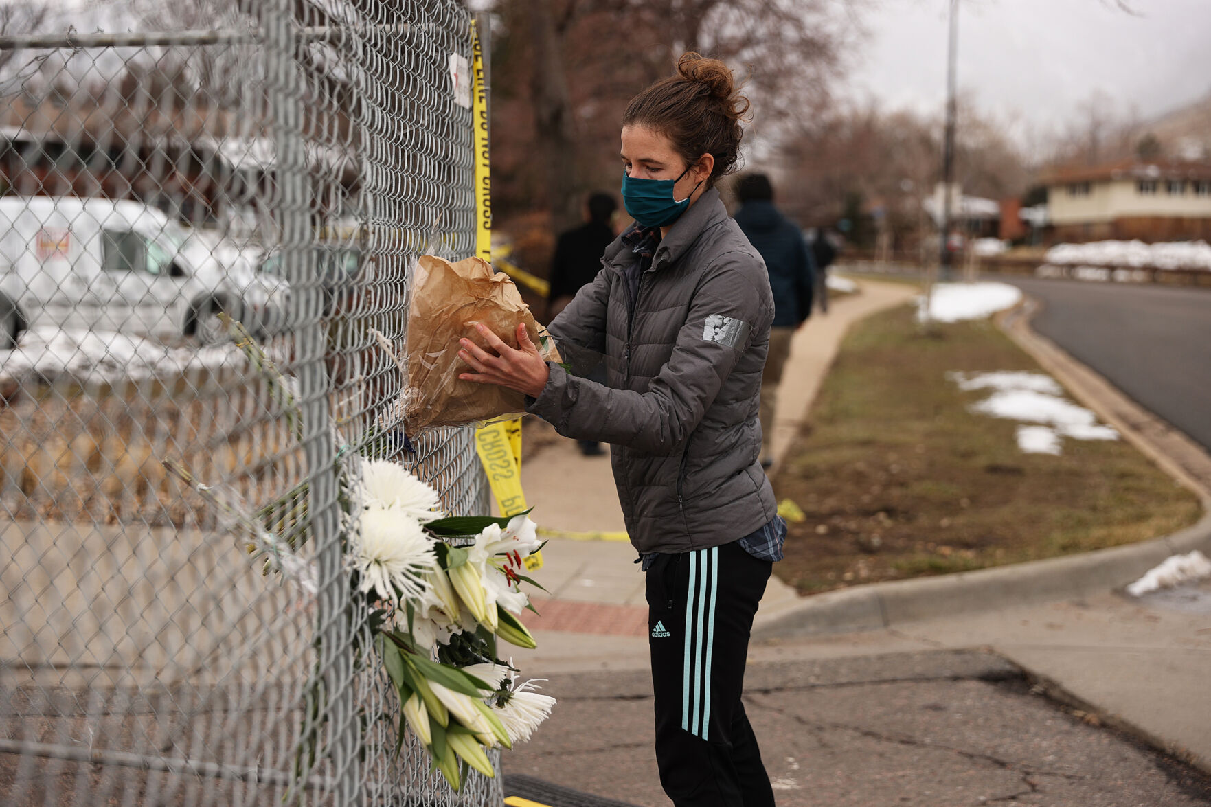 A woman adjusts a bouquet of flowers in the perimeter fence around the King Soopers on Table Mesa Drive in Boulder on March 23, 2021. A gunman killed 10 people in a mass shooting at the store the day before. (Forrest Czarnecki/The Gazette) (Forrest Czarnecki)