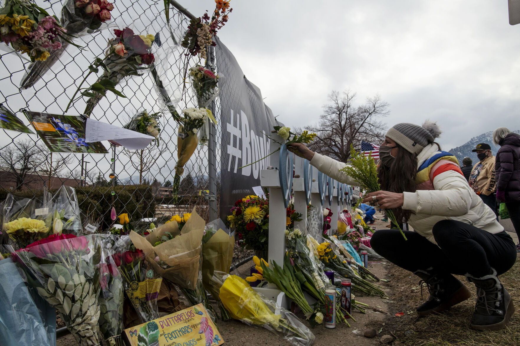 Osha Waters places flowers on a cross for Tralona Bartkowiak, who was one of 10 killed including a police officer in a mass shooting at King Soopers supermarket on Monday, outside the fence in font of the store in Boulder, Colo., on Wednesday, March 24, 2021. (Chancey Bush/ The Gazette) (Chancey Bush)