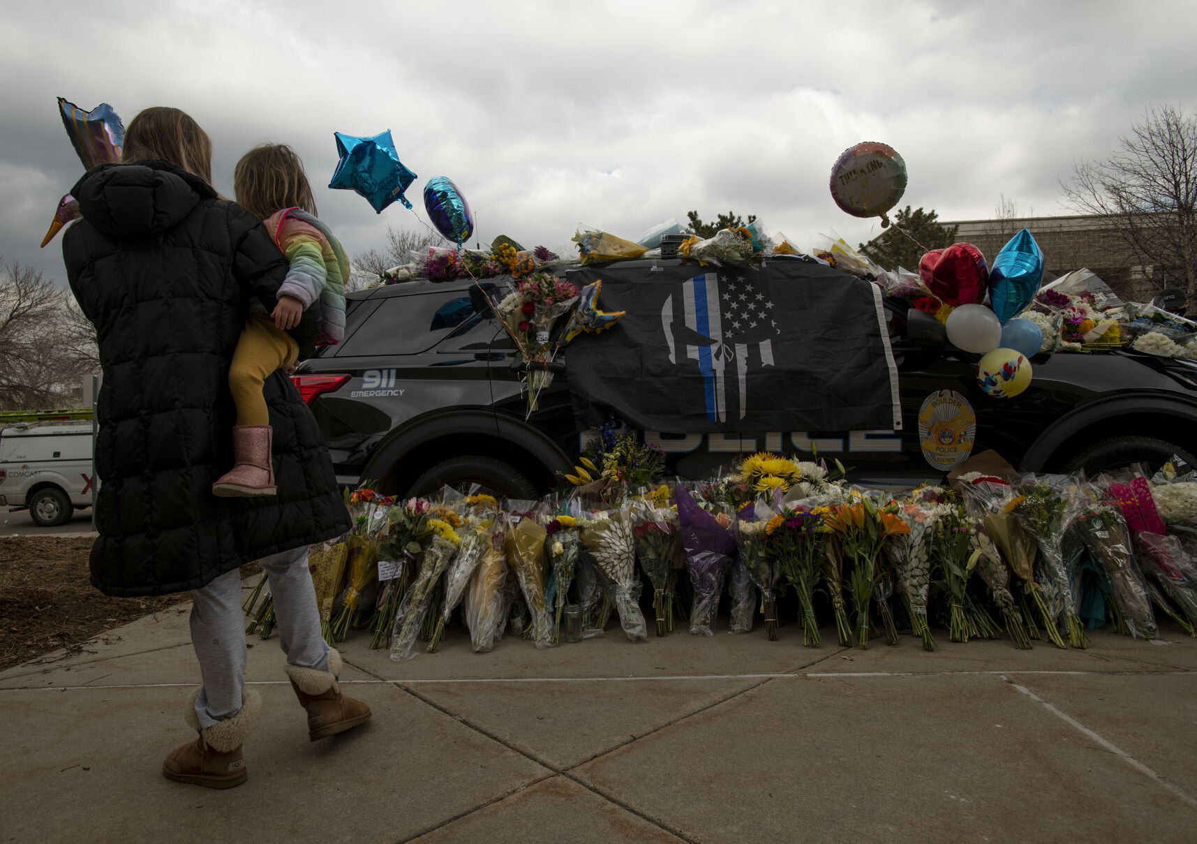Courtney Shearon holds her daughter Charlotte, 2, while they pay their respects to officer Eric Talley, who was killed in a mass shooting with nine others at King Soopers supermarket on Monday, outside the Boulder Police Department in Boulder, Colo., on Wednesday, March 24, 2021. Community members payed their respects to officer Talley by leaving flowers and other items on his patrol car outside the station.(Chancey Bush/ The Gazette) (Chancey Bush)