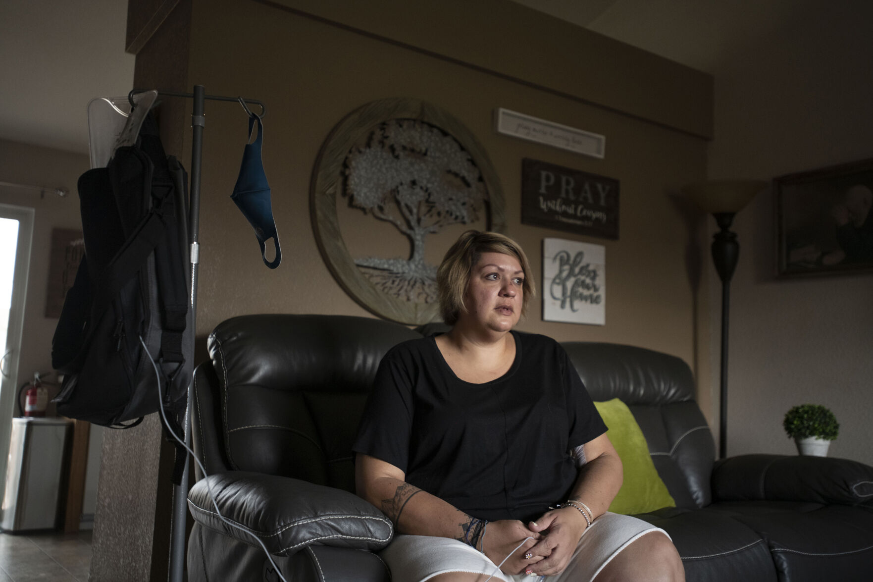 Kendra Lippy, 38, left, sits in her living room with with her total parenteral nutrition bag at her home in Colorado Springs on May 14, 2020. After receiving the Johnson & Johnson COVID-19 vaccine this spring, Lippy suffered severe side-effects and almost died. Lippy developed blood clots that destroyed her small intestine. She spent 33 days in the hospital as her doctors tried to determine the source of the problem. She was in an induced coma for 22 days with feeding tubes. Doctors removed most of her small intestine, leaving only 90 centimeters. (Chancey Bush/ The Gazette) (Chancey Bush/ The Gazette)