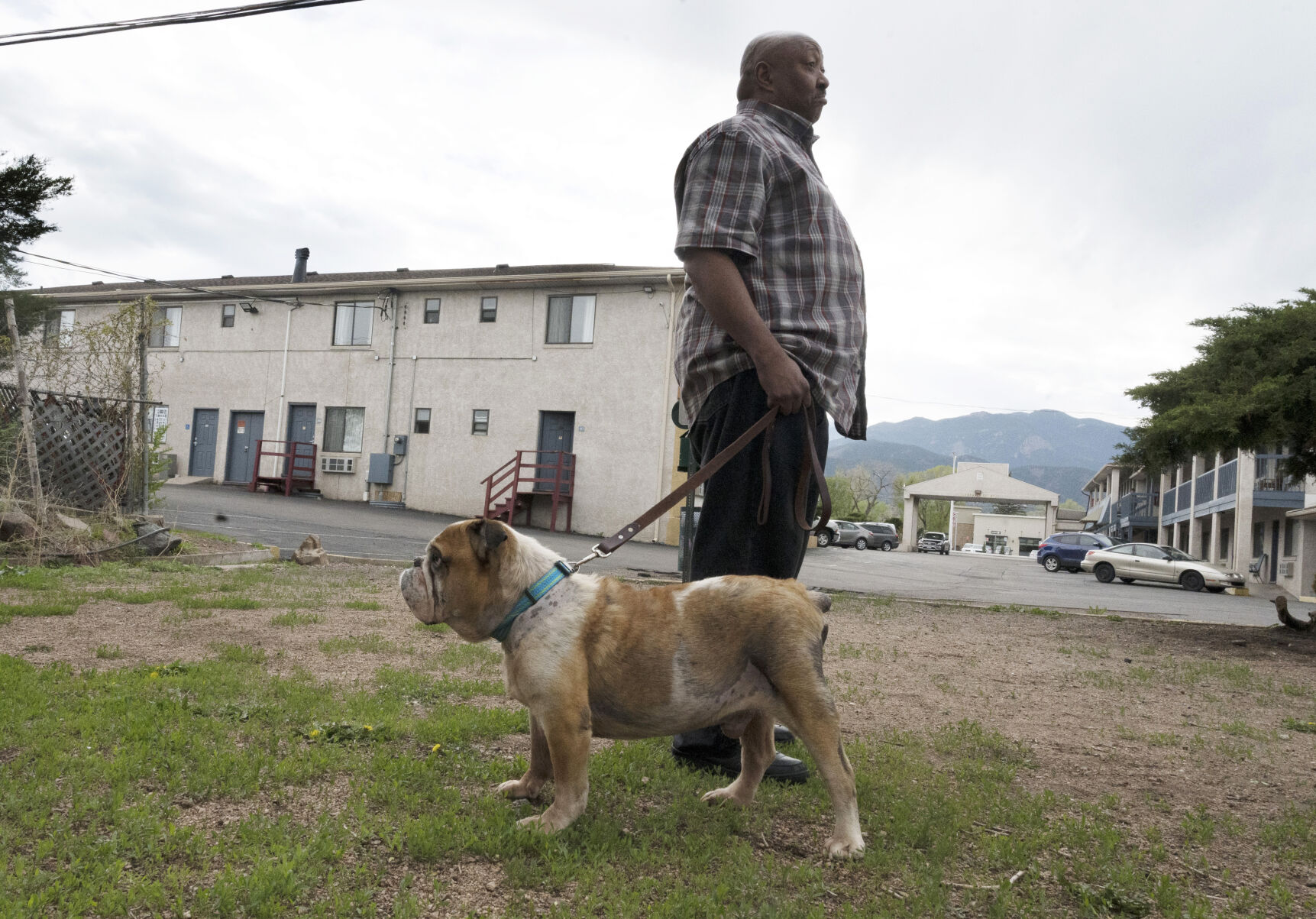 John Wilson takes his dog, Triton, for a walk Thursday at the motel where he and his family are currently living in Colorado Springs. (JERILEE BENNETT, THE GAZETTE)