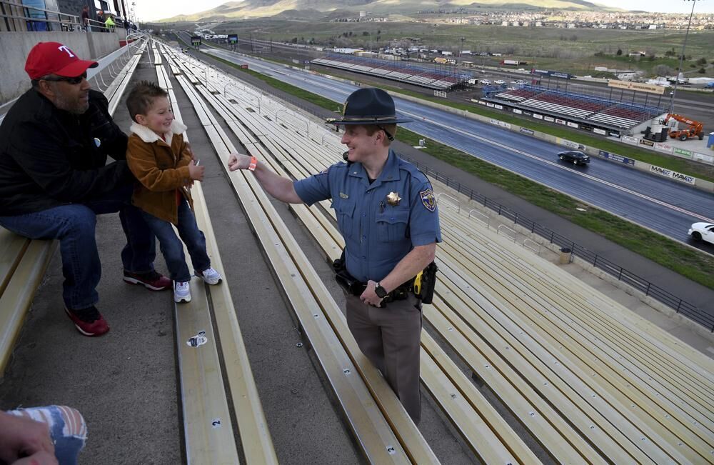 Colorado State Patrol Trooper Josh Lewis fist bumps 3-year-old Lincoln Delagarza, of Northglenn, Colorado, before racing begins at Bandimere Speedway west of Denver on May 5, 2021. The State Patrol runs a program called