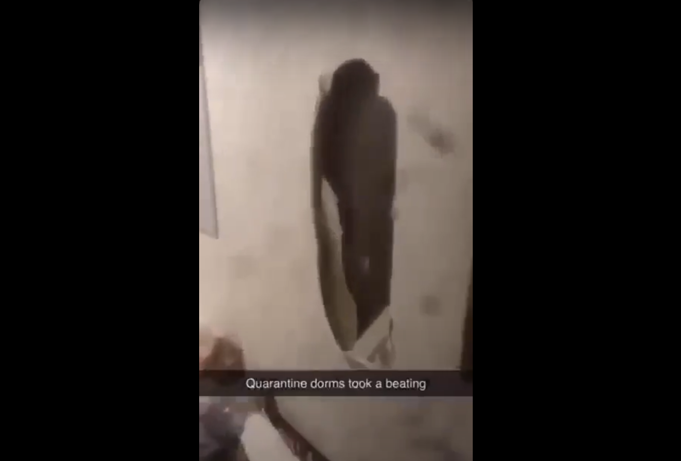 A frame from a video shows a hole in the wall in the hallway of one of the isolation dorms. (frame from video by Hays Gott)