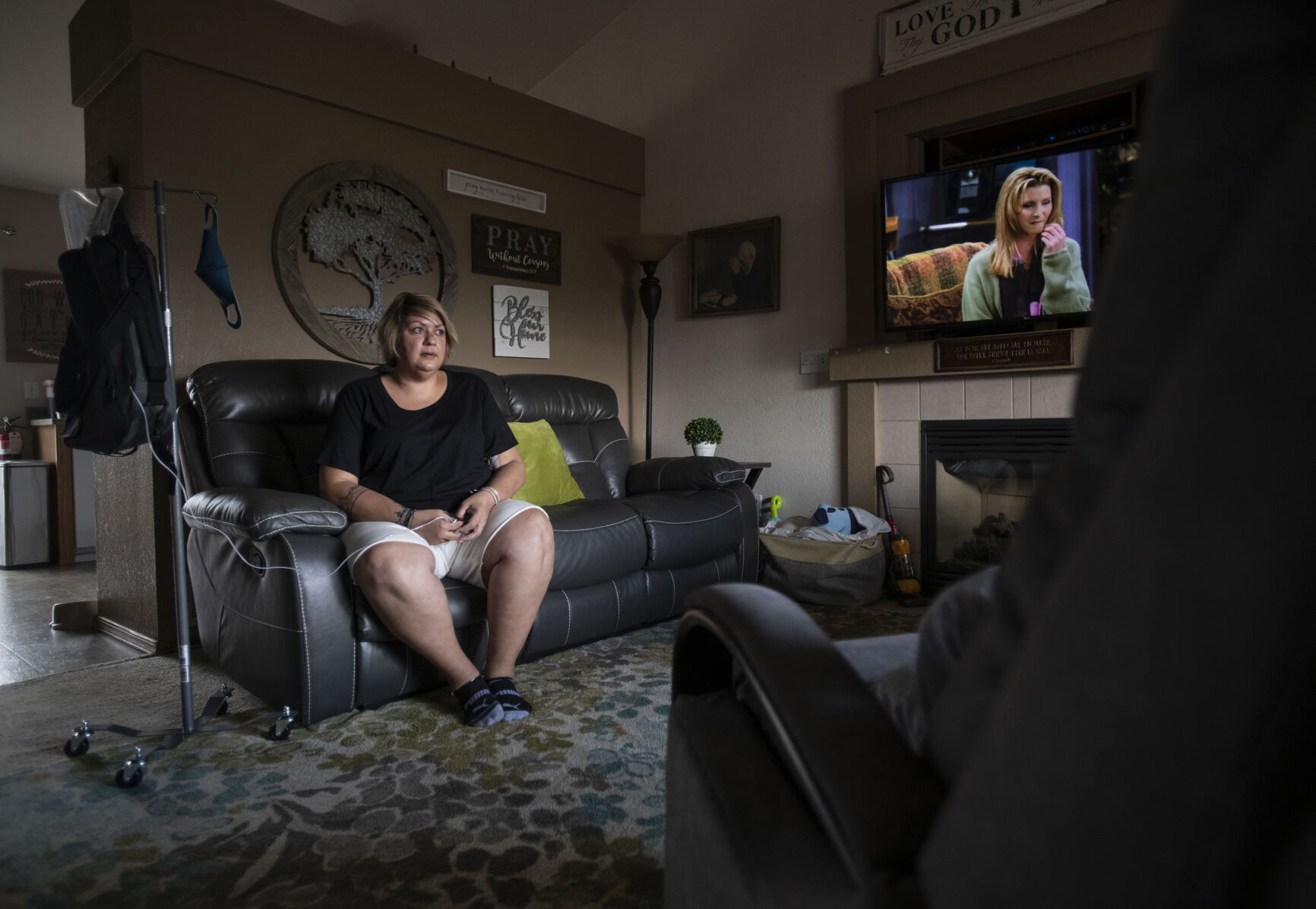 Kendra Lippy, 38, left, sits in her living room with with her total parenteral nutrition bag at her home in Colorado Springs on May 14, 2020. After receiving the Johnson & Johnson COVID-19 vaccine this spring, Lippy suffered severe side-effects and almost died. Lippy developed blood clots that destroyed her small intestine. She spent 33 days in the hospital as her doctors tried to determine the source of the problem. She was in an induced coma for 22 days with feeding tubes. Doctors removed most of her small intestine, leaving only 90 centimeters. (Chancey Bush/ The Gazette) (Chancey Bush/ The Gazette)