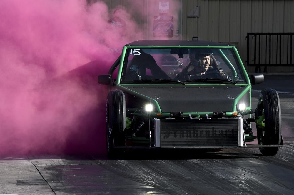 A racer spews pink smoke from his car during a