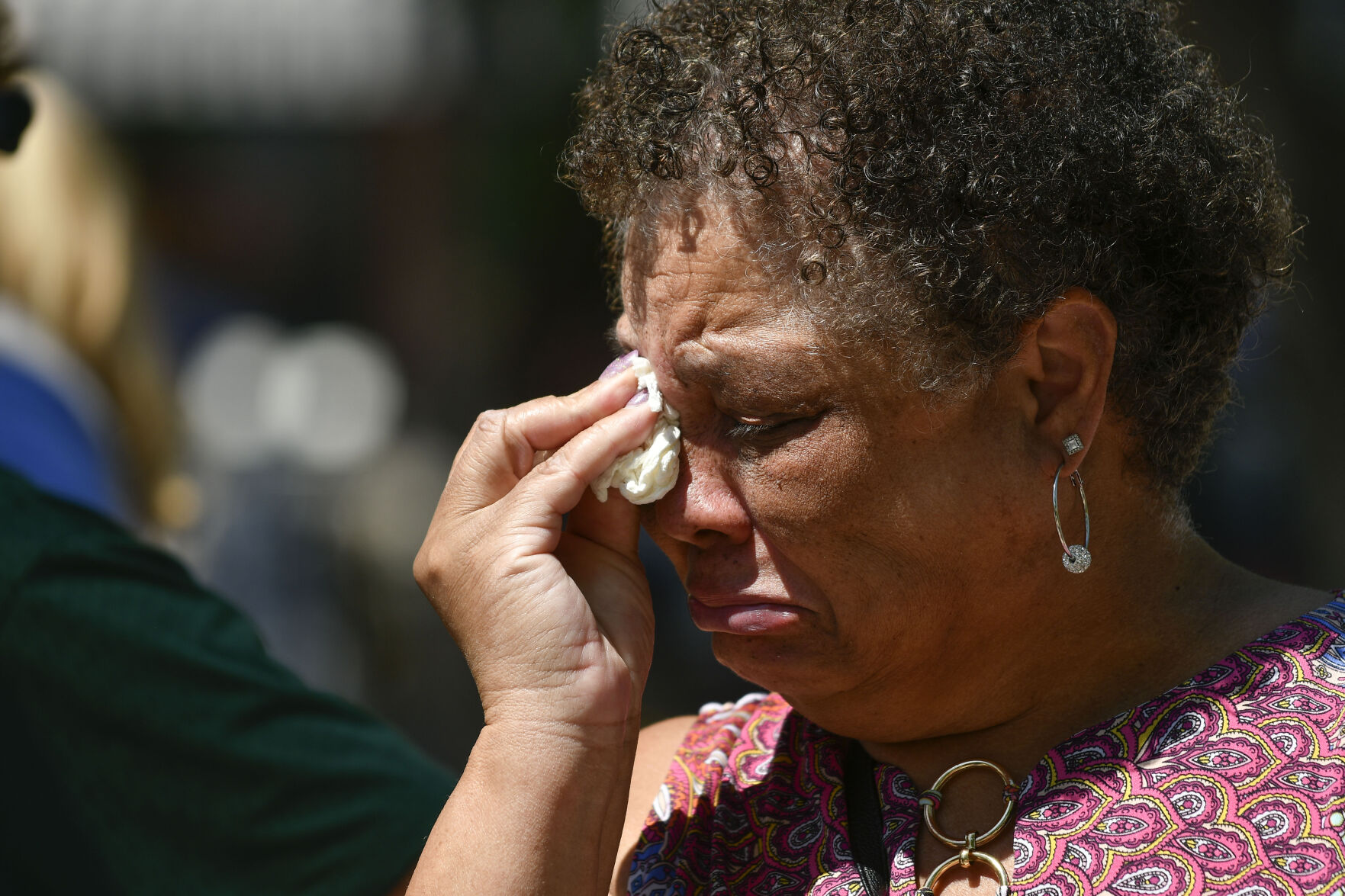 JUNE 22, 2021 - Melinda Perry a former Social Worker at Oberon Middle School wipes her tears as staff members gather at the fountain in Olde Town Arvada where a shooting left three people dead, including Arvada veteran police officer Gordon Beesley, another person was also killed after being shot by the gunman and the suspect was also shot and killed. The staff from Oberon Middle School marched to the police station where the officers patrol car is on display covered with flowers and several flags. (Photo by John Leyba) (John Leyba)