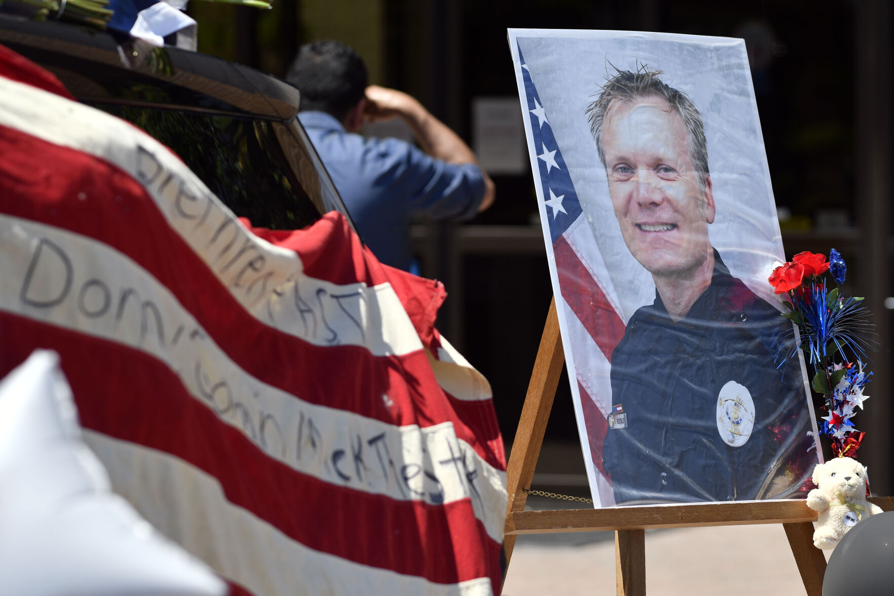 Arvada veteran police officer Gordon Beesley portrait on display next to his patrol car at the station covered in flowers and flags. Beesley was killed in a shooting in Olde Town Arvada. The suspect was also shot and killed. (The Colorado Sun via the Associated Press)