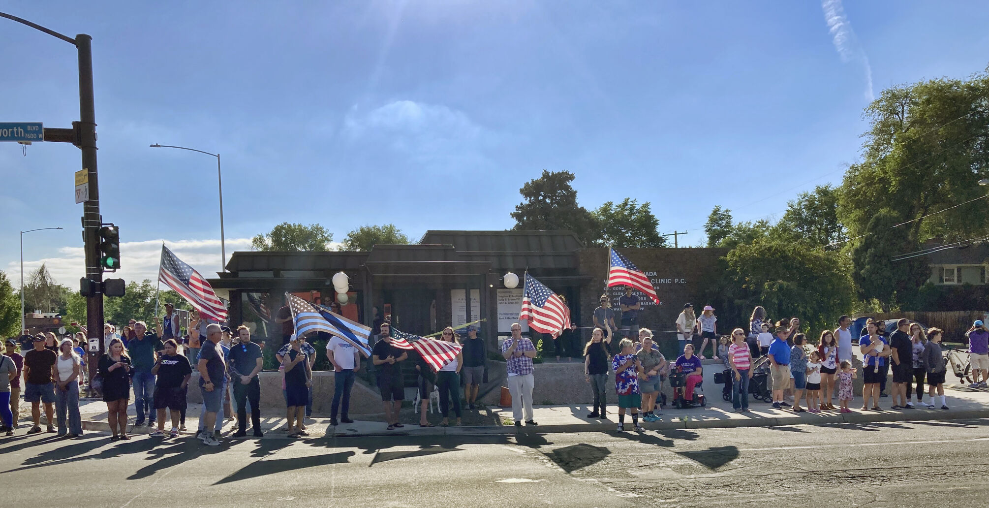 People line the street with flags during a procession in honor of an officer who was fatally shot in Arvada, Colo., Monday, June 21, 2021. A gunfight between two men and police officers at a shopping district in a Denver suburb left an officer and one of the suspects dead, authorities said Monday. (AP Photo/Colleen Slevin) (Colleen Slevin)