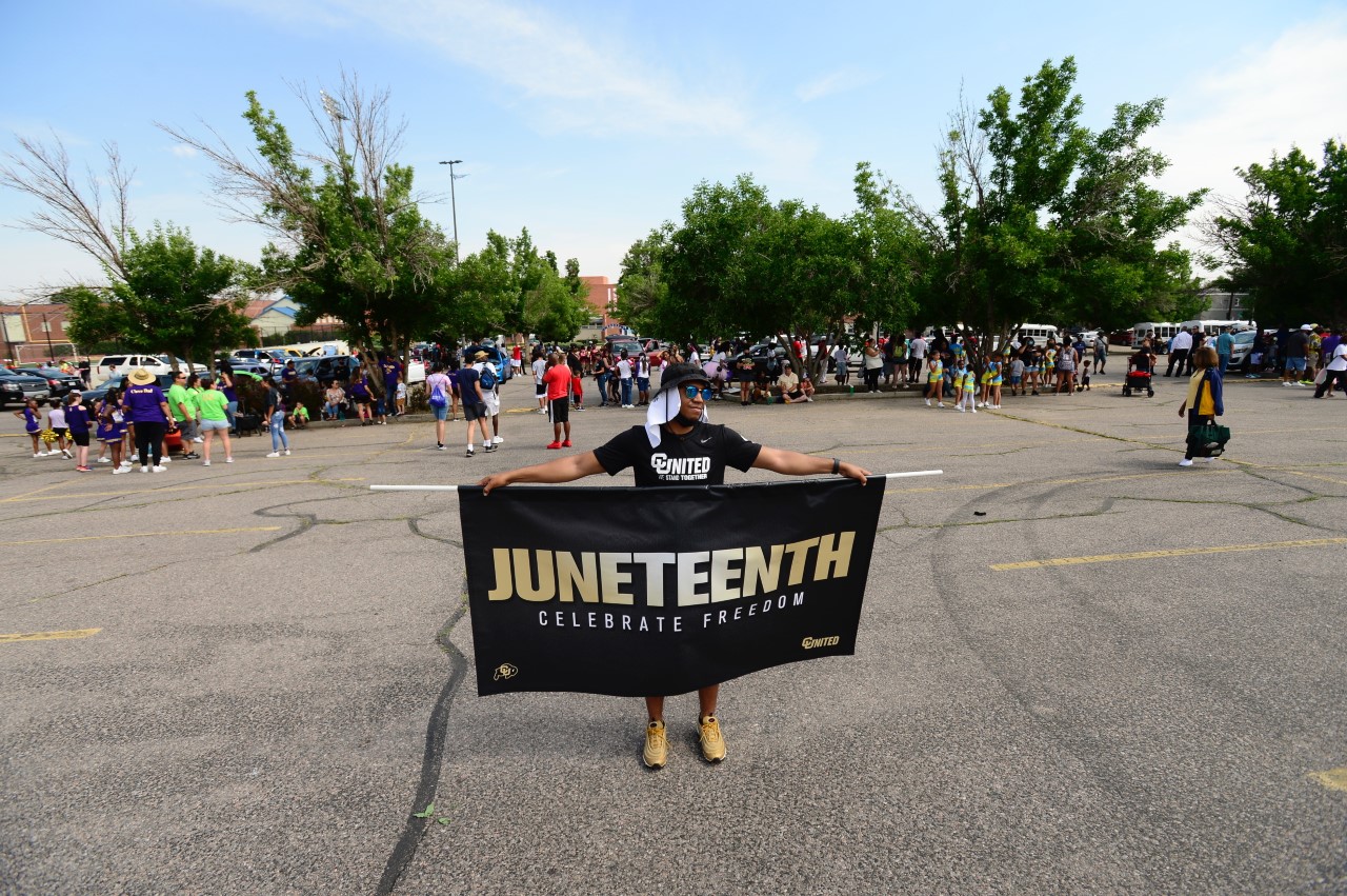 Dawon Baker stands in the middle of the parking lot at Maialetti High School waiting for the start of Juneteenth parade to start. Dawon will lead the parade from Manual to Five Points (John Leyba)
