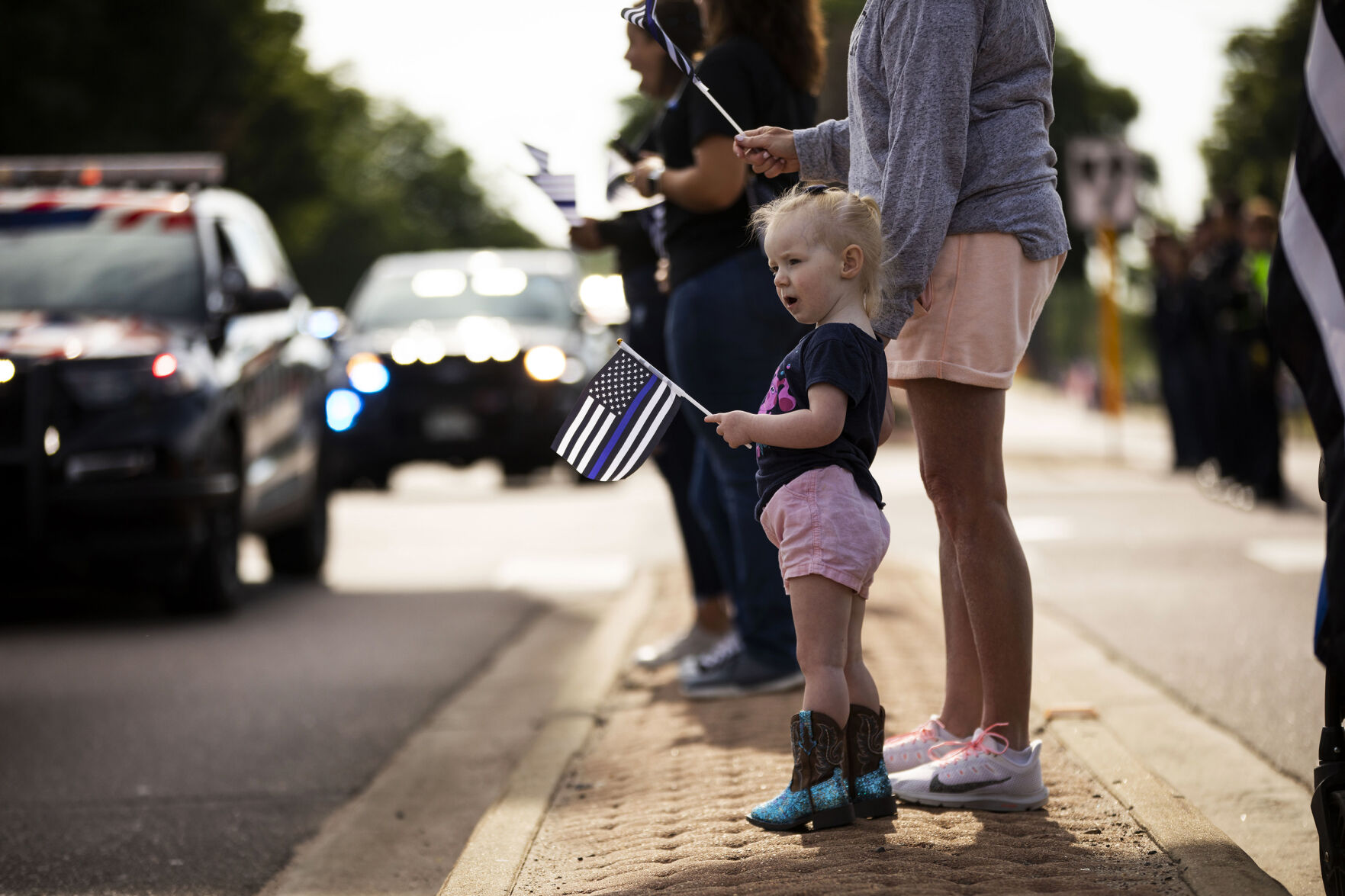 Skyler Willden, 2, watches as hundreds of law enforcement and first responder vehicles pass by during a funeral procession for slain Arvada police officer Gordon Beesley in Lafayette, Colo., on Tuesday, June 29, 2021. A funeral was held at the Flatirons Community Church for officer Beesley, who was a 19-year veteran of the Arvada Police Department. Officer Beesley was killed by a gunman in Olde Town Arvada plaza on June 21, 2021. (Chancey Bush/ The Gazette) (Chancey Bush)