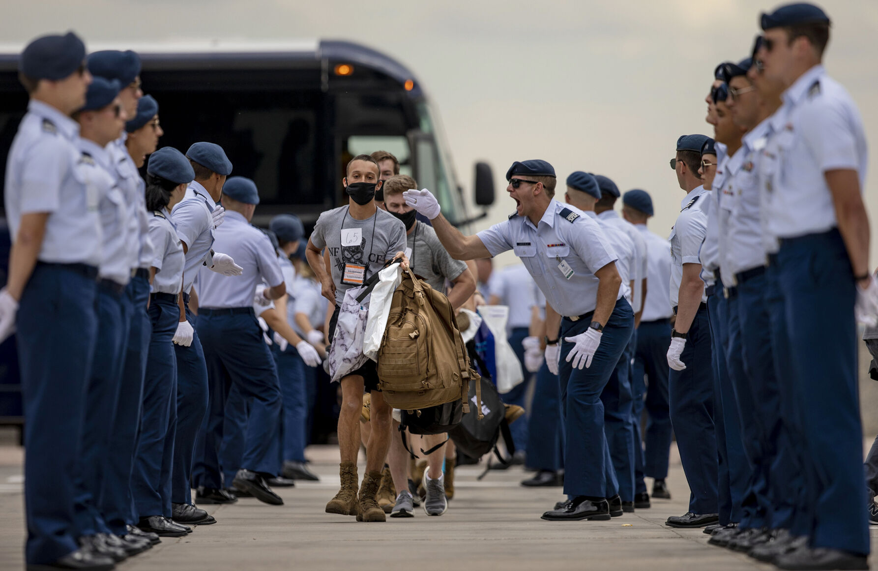 Incoming cadets run from the bus to the footprints as cadre members yell at them to hurry up during In-Processing Day at the United States Air Force Academy in Colorado Springs, Colo., on Thursday, June 24, 2021. Over 1,100 incoming freshman will undergo six weeks of basic training before officially becoming cadets.(Chancey Bush/ The Gazette) (Chancey Bush/ The Gazette)