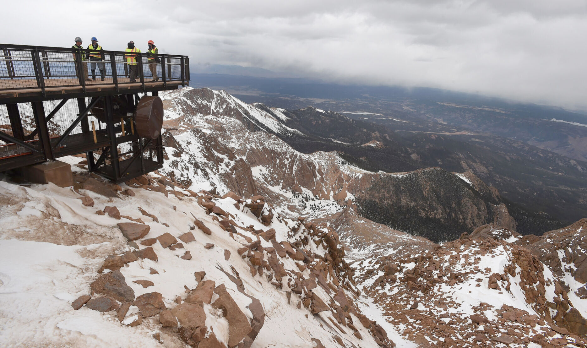 While taking a tour of the progress of the Pikes Peak Summit Visitor Center, city officials and construction managers walk out onto one of the new overlooks. One of the showcases is a walkway that partially encircles the summit with a variety of overlooks that will offer breathtaking views of the Pikes Peak region. People of all abilities will be able to access the walkway. Officials say the new visitor center is scheduled to open sometime in June. (The Gazette, Jerilee Bennett)