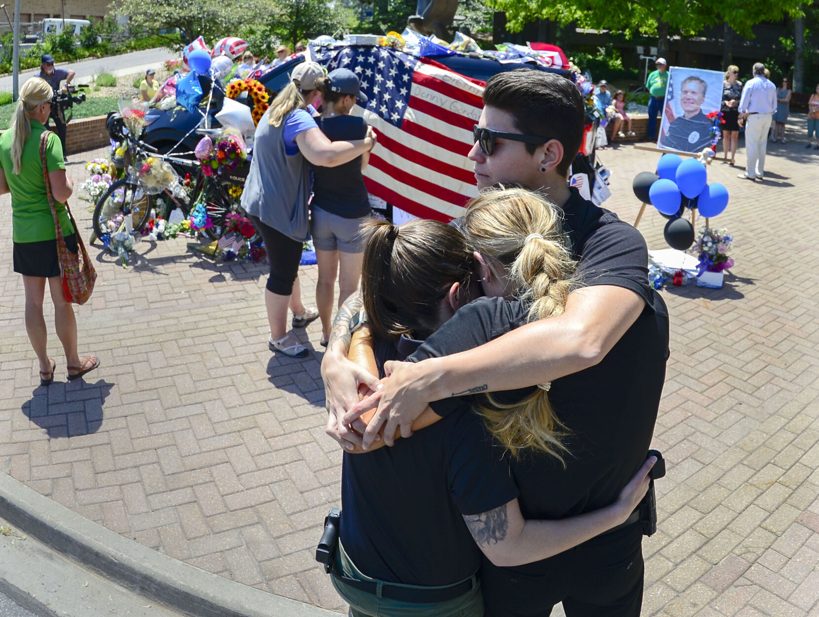JUNE 22, 2021 - Three Arvada Police officers embrace as they pay their respects to fallen officer Gordon Beesley at his car located in front of the police station in Arvada. The shooting took place in Olde Town Arvada where the shooting left three people dead, including Arvada veteran police officer Gordon Beesley, another person was also killed after being shot by the gunman and the suspect was also shot and killed. Beesley car and mountain bike are decorated in flowers and flags. (Photo by John Leyba) (John Leyba)