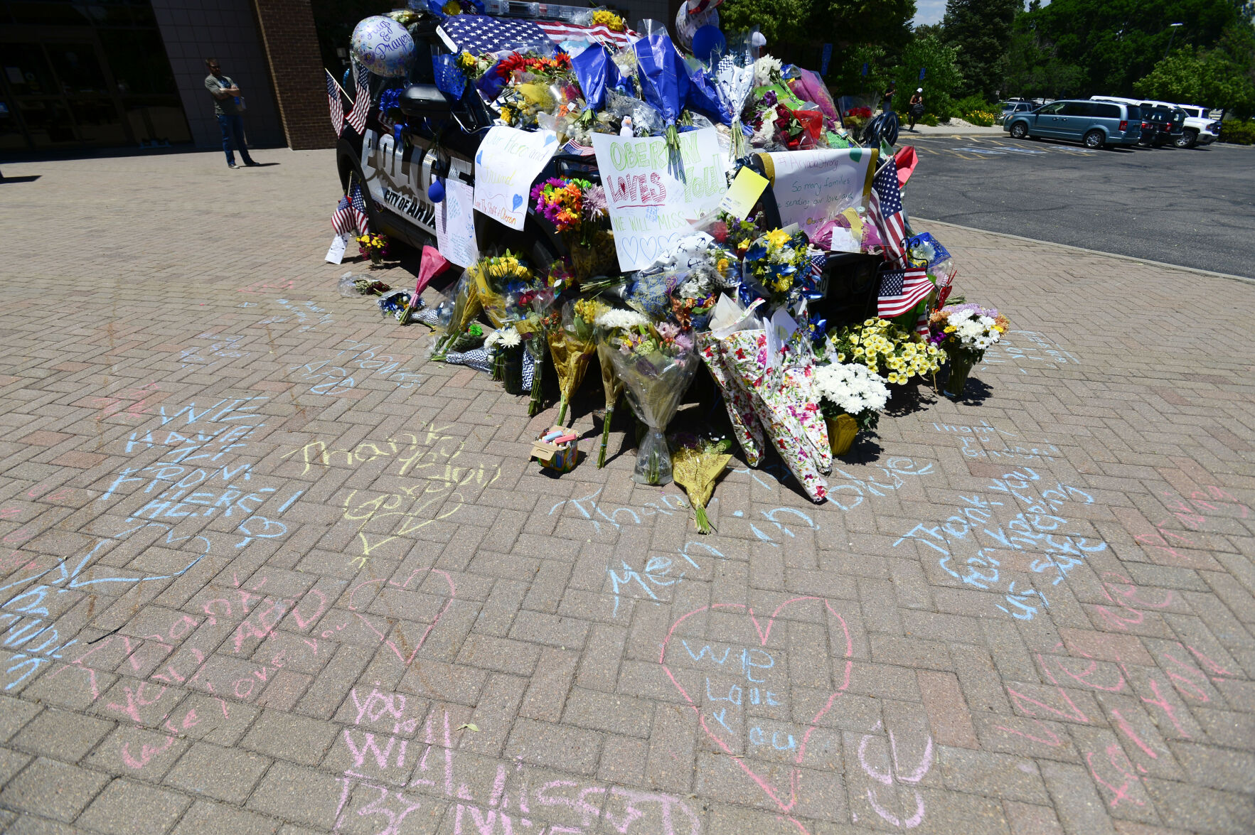 JUNE 22, 2021 - The police station where the officers patrol car is on displayed is covered with flowers and several flags as the memorial grows. Staff members from Oberon Middle School gathered at the station to pay their respects. Beesley was a Resource Officer at Oberon Middle School. The shooting took place in Olde Town Arvada where the shooting left three people dead, including Arvada veteran police officer Gordon Beesley, another person was also killed after being shot by the gunman and the suspect was also shot and killed. (Photo by John Leyba) (John Leyba)