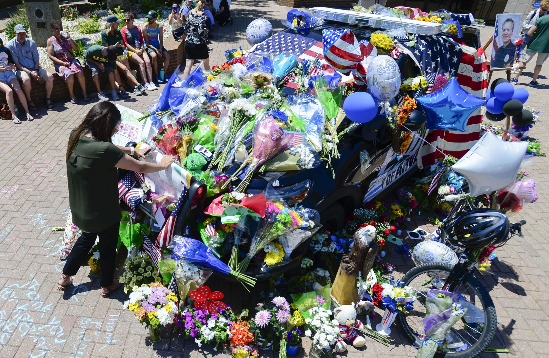 JUNE 22, 2021 - Tara Peña pays her respect to fallen officer Gordon Beesley after he was shot and killed in a shooting at Olde Town Arvada. Peña was a former principal at Oberon Middle School and worked with Beesley who was the Resource Officer at the school. The police station where the officers patrol car is on displayed is covered with flowers and several flags as the memorial grows.(Photo by John Leyba) (John Leyba)