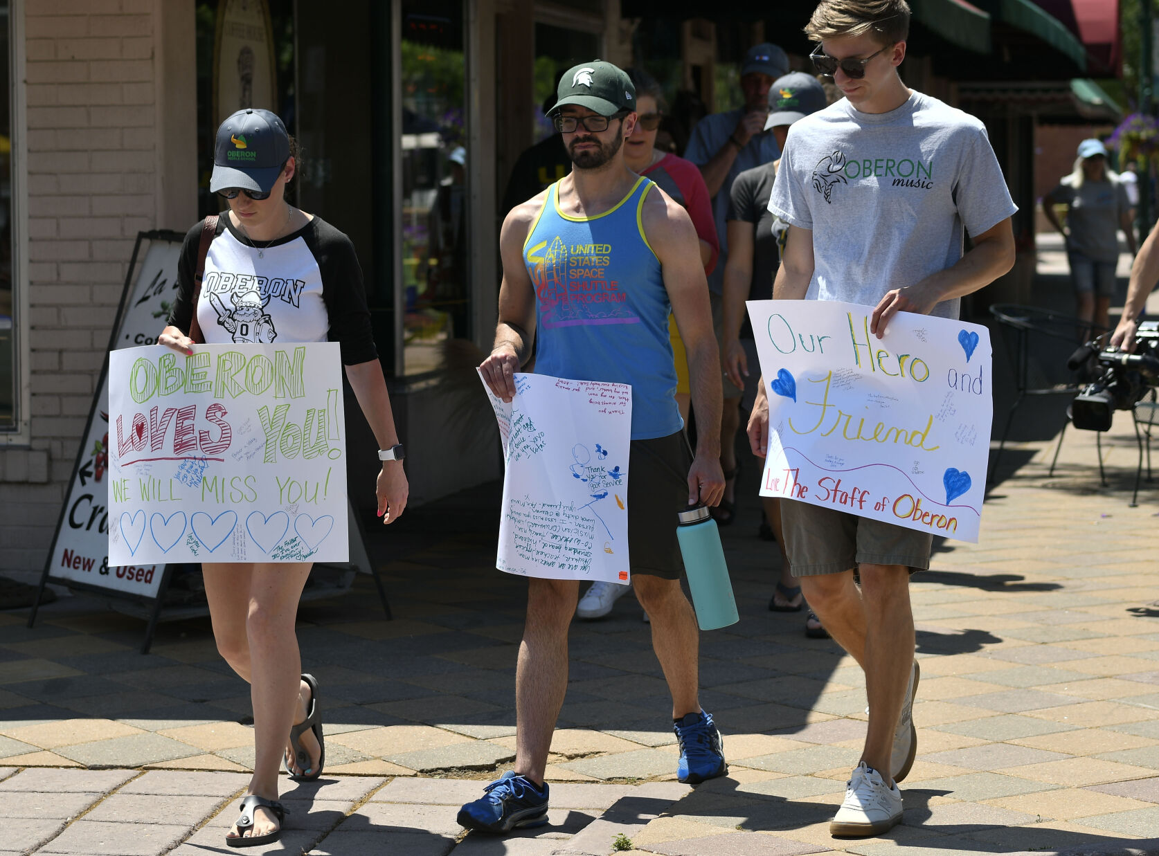 JUNE 22, 2021 - Staff members from Oberon Middle School walk to the police station with their signs to pay their respects to fallen officer Gordon Beesley. A shooting at the fountain in Old Town Arvada left three people dead, including Arvada veteran police officer Gordon Beesley, another person was also killed after being shot by the gunman and the suspect was also shot and killed. The staff from Oberon Middle School marched to the police station where the officers patrol car is on display covered with flowers and several flags. (Photo by John Leyba) (John Leyba)