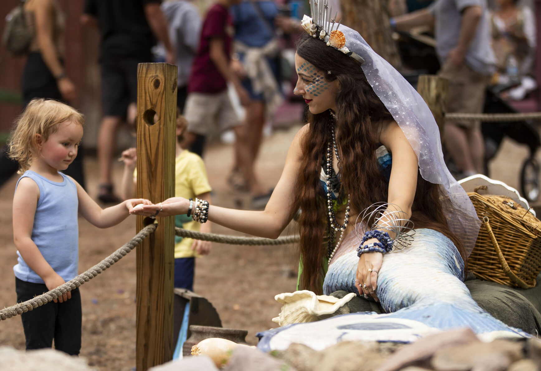 Aysun the mermaid gives a seashell to Teagan Connelly, 3, on opening day of the 2021 Colorado Renaissance Festival. (Chancey Bush, Gazette file)