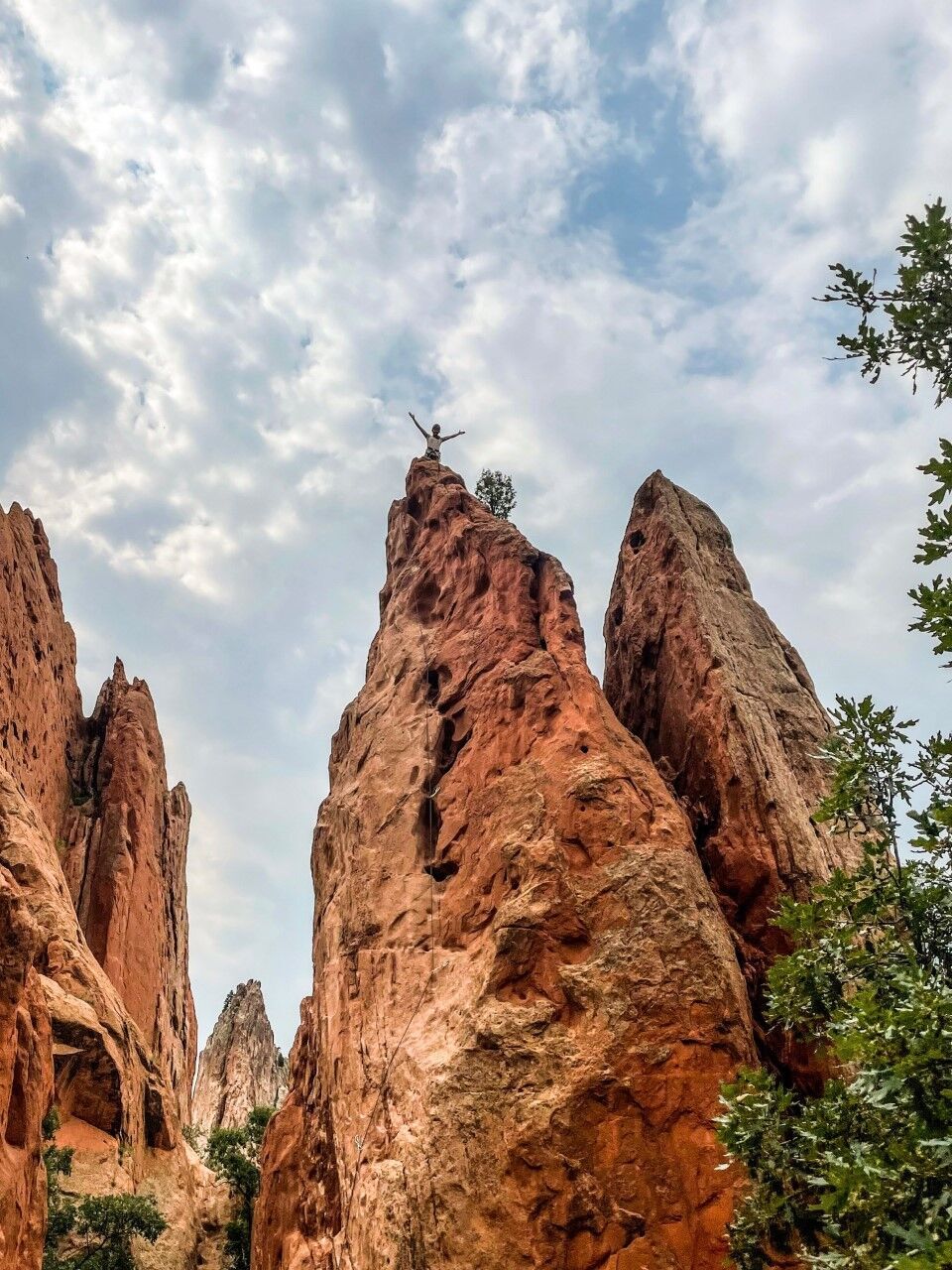 Paige Claassen stretches her arms at the top of the Red Twin Spires formation at Garden of the Gods. Photo Credit: Spencer McKee.