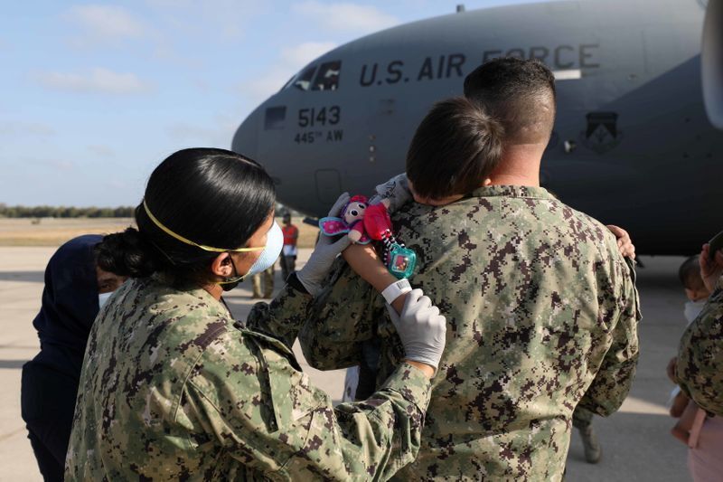 FILE PHOTO: Naval Station (NAVSTA) Rota sailors attend to an Afghan child, who is part of group of 450 Afghan citizens evacuated from Kabul, as they left a U.S. Air Force C-17 Globemaster III transport plane after arriving from Kuwait, at Naval Station (NAVSTA) Rota Air Base in Rota, southern Spain, August 27, 2021. U.S. Navy Mass Communication Specialist 2nd Class Katie Cox/Handout via REUTERS (U.S. NAVY)