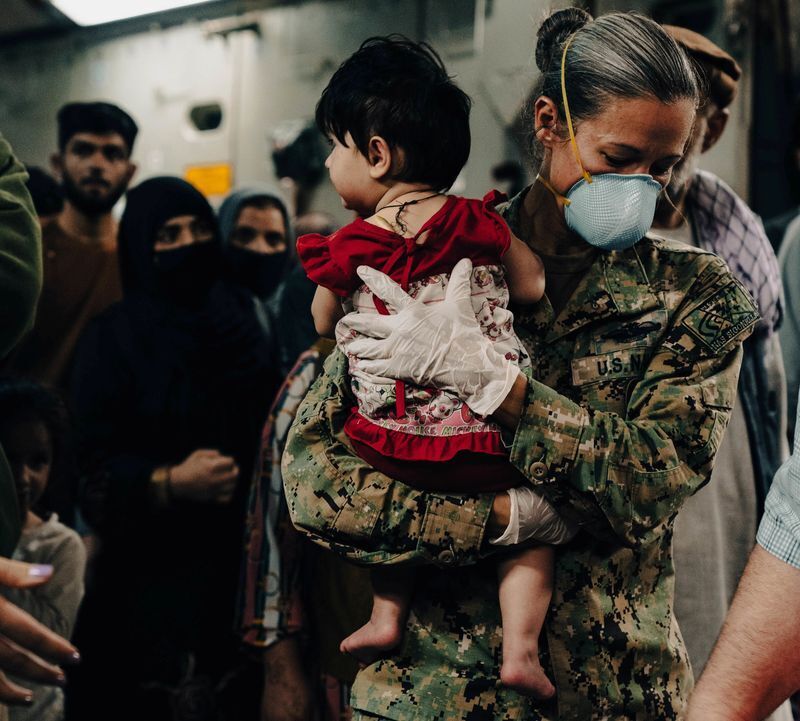 Naval Air Station Sigonella Command Master Chief Anna Wood carries an Afghanistan evacuee off a U.S. Air Force C- 17 Globemaster lll at Naval Air Station Sigonella, August 22, 2021. U.S. Marine Corps/Sgt. William Chockey/Handout via REUTERS (US MARINES)