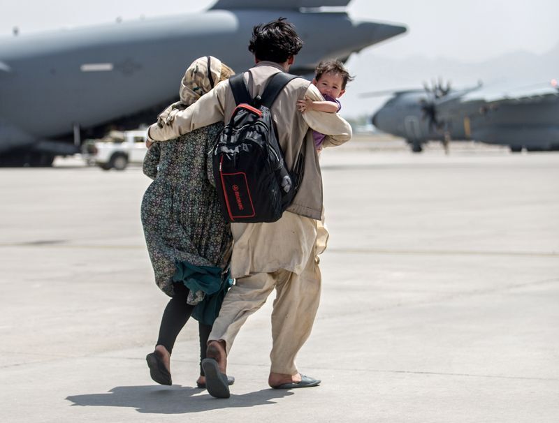 A family walks towards a U.S. Air Force Boeing C-17 Globemaster III during an evacuation at Hamid Karzai International Airport, Afghanistan, August 22, 2021. Picture taken August 22, 2021. U.S. Marine Corps/Sgt. Samuel Ruiz/Handout via REUTERS (US MARINES)