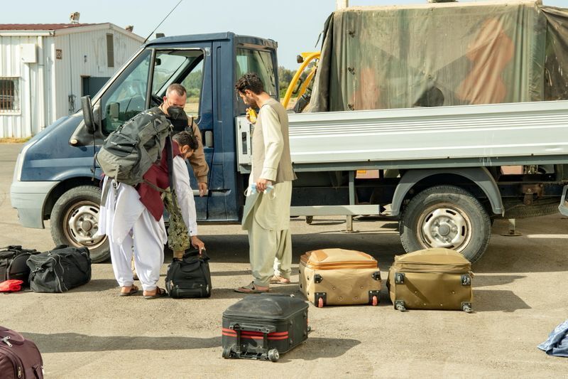 A Naval Station (NAVSTA) Rota sailor attends to Afghan men, who are part of group of 450 Afghan citizens evacuated from Kabul, as they left a U.S. Air Force C-17 Globemaster III transport plane after arriving from Kuwait, at Naval Station (NAVSTA) Rota Air Base in Rota, southern Spain, August 27, 2021. Picture taken August 27, 2021. U.S. Navy Mass Communication Specialist 2nd Class John Owen/Handout via REUTERS (U.S. NAVY)