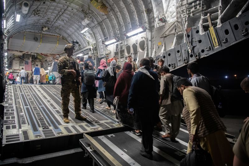 Afghans board a U.S. Air Force C-17 Globemaster III transport plane during an evacuation at Hamid Karzai International Airport, Afghanistan, August 22, 2021. U.S. Air Force/Handout via REUTERS (US AIR FORCE)