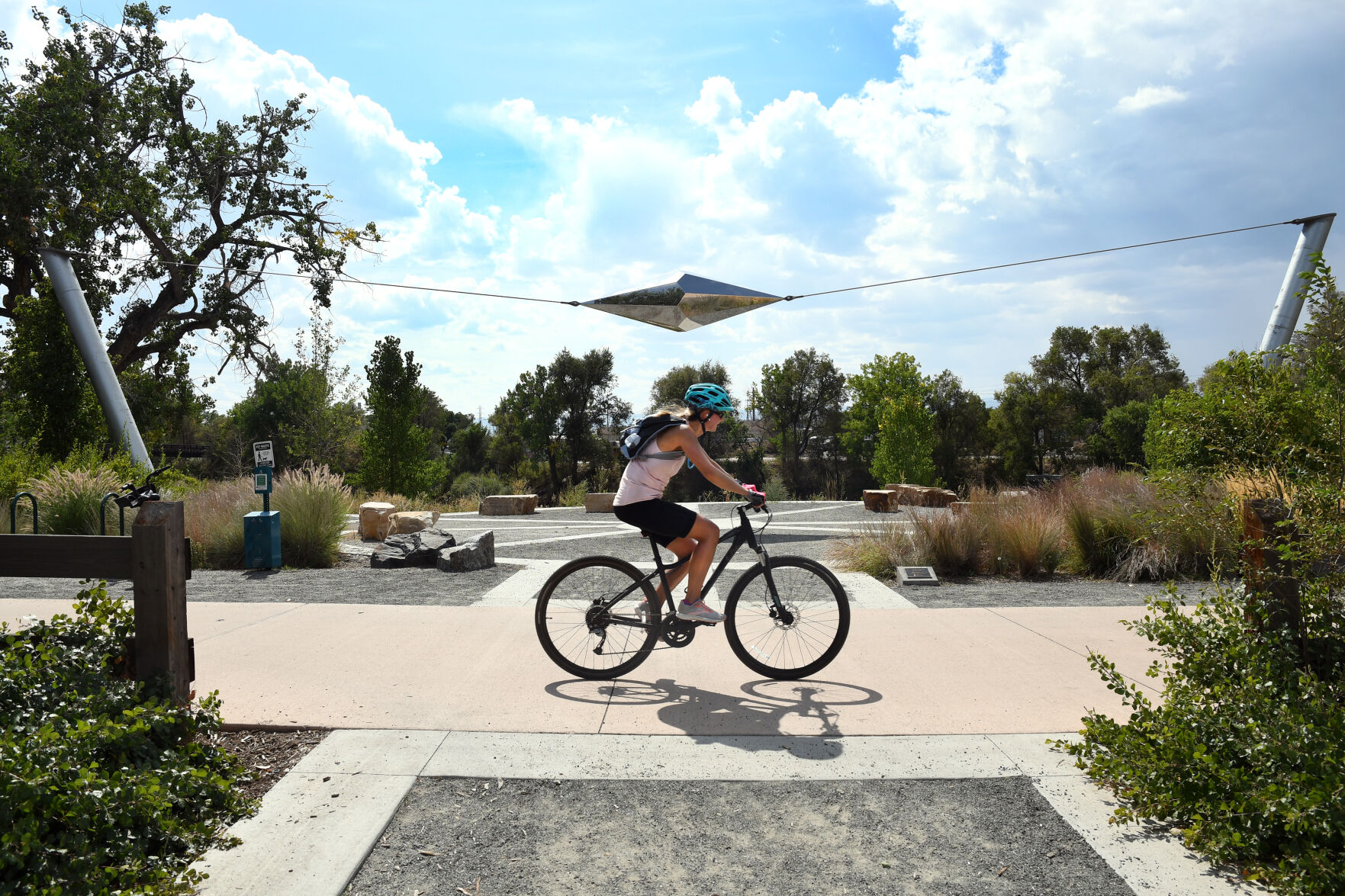 A cyclist rides under a new art installation, erected in 2020 at Grant-Frontier Park in Denver. “Infinite Span” by Michael Buckley, was installed as part of the Denver Art Program. (Kathryn Scott)