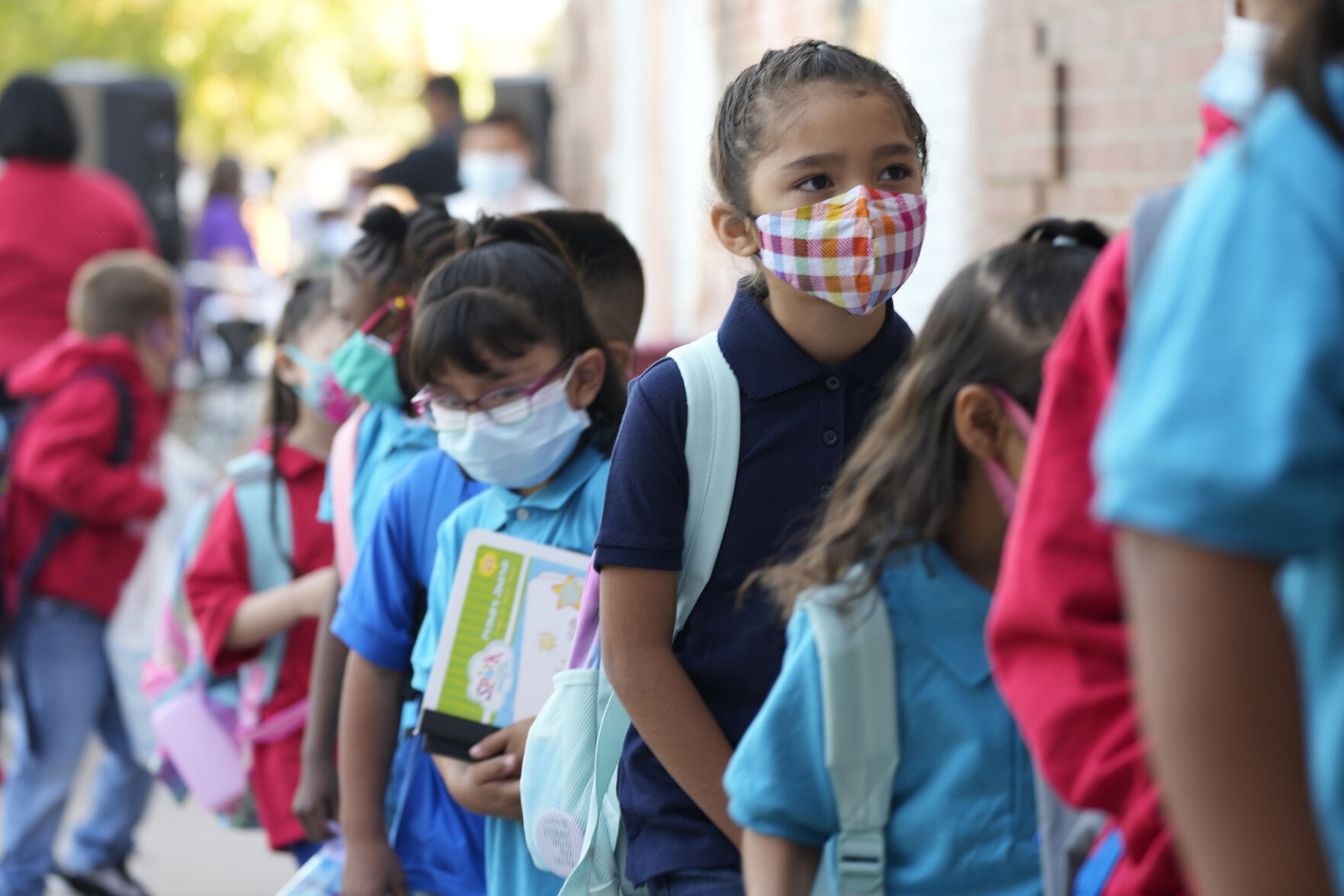 Students don face coverings as they wait in line to enter for the first day of in-class learning since the start of the pandemic at Garden Place Elementary School, Monday, Aug. 23, 2021, in north Denver. All students, visitors and staff are required to wear face coverings while in Denver Public Schools regardless of vaccination status with the start of the school year. (David Zalubowski - staff, AP)