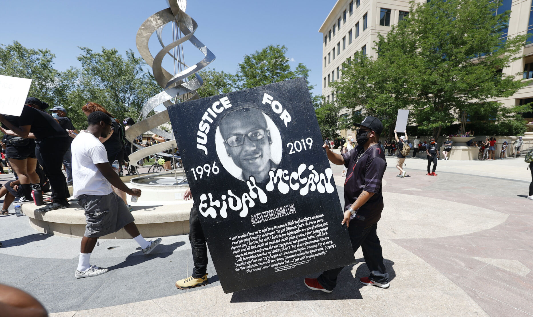 In this June 27, 2020, file photo, demonstrators carry a giant placard during a rally and march over the death of Elijah McClain outside the police department in Aurora, Colo. Colorado Attorney General Phil Weiser announced on Wednesday, Sept. 1, 2021, that a grand jury has returned a 32-count indictment charging three Aurora police officers and two paramedics, including manslaughter and criminally negligent homicide charges for each. ((AP Photo/David Zalubowski, File))