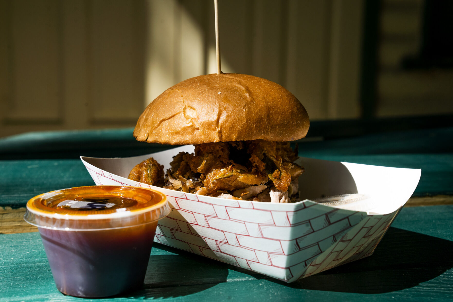 The Devil's Elbow, a pulled pork sandwich on a brioche bun, topped with fried pickles and a side of the standard bbq sauce on Friday, September 24, 2021 at Switchback Smokehouse in Kittredge. (Photo by Katie Klann/The Gazette) (Katie Klann The Gazette)