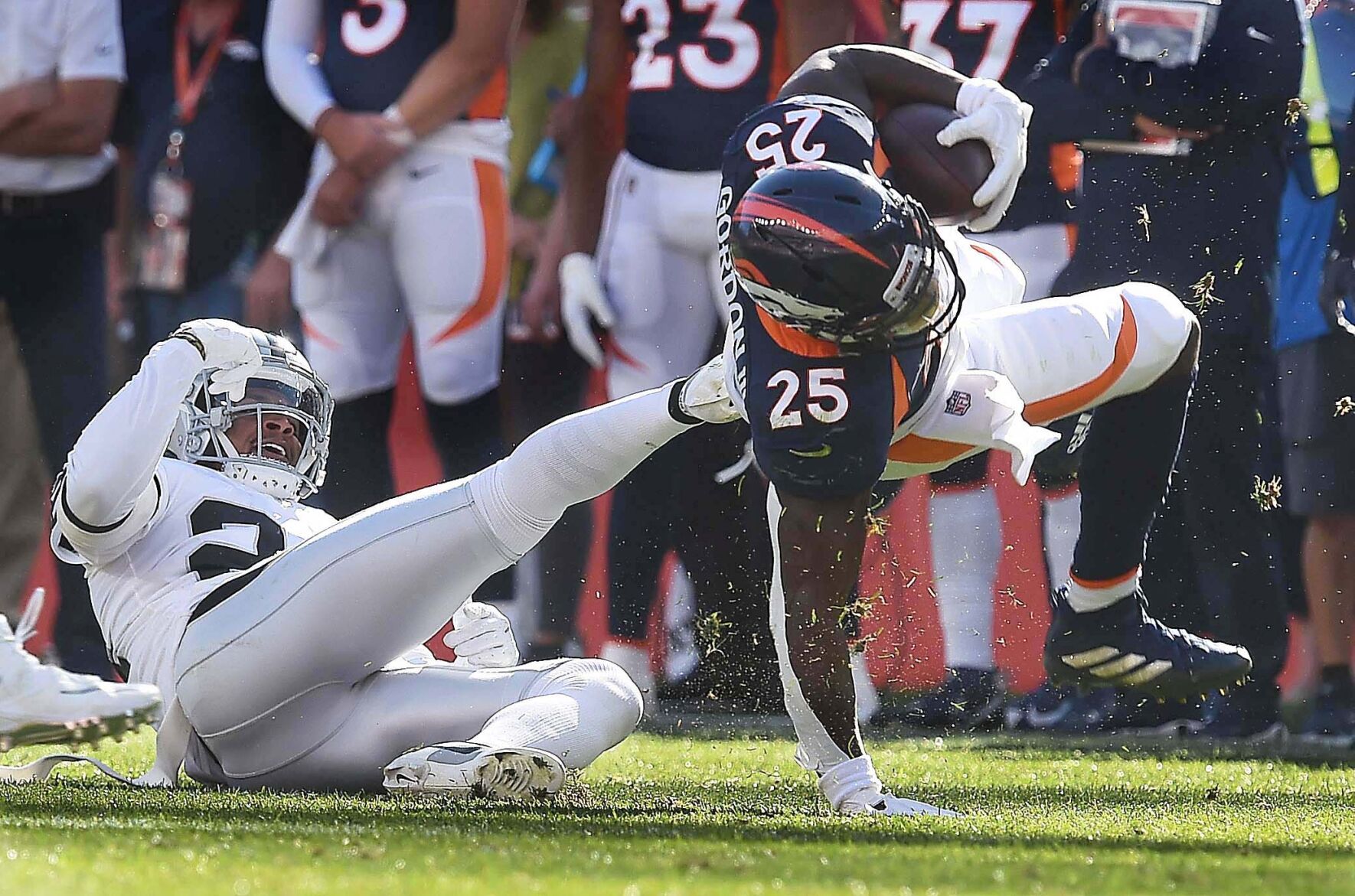 Broncos running back Melvin Gordon III gets a kick from Raiders safety Johnathan Abram as he twists for extra yards during the second quarter of a game at Empower Field at Mile High Stadium on Sunday, Oct. 17, 2021. The Broncos were defeated 34-24. (Photo by Jerilee Bennett, The Gazette)